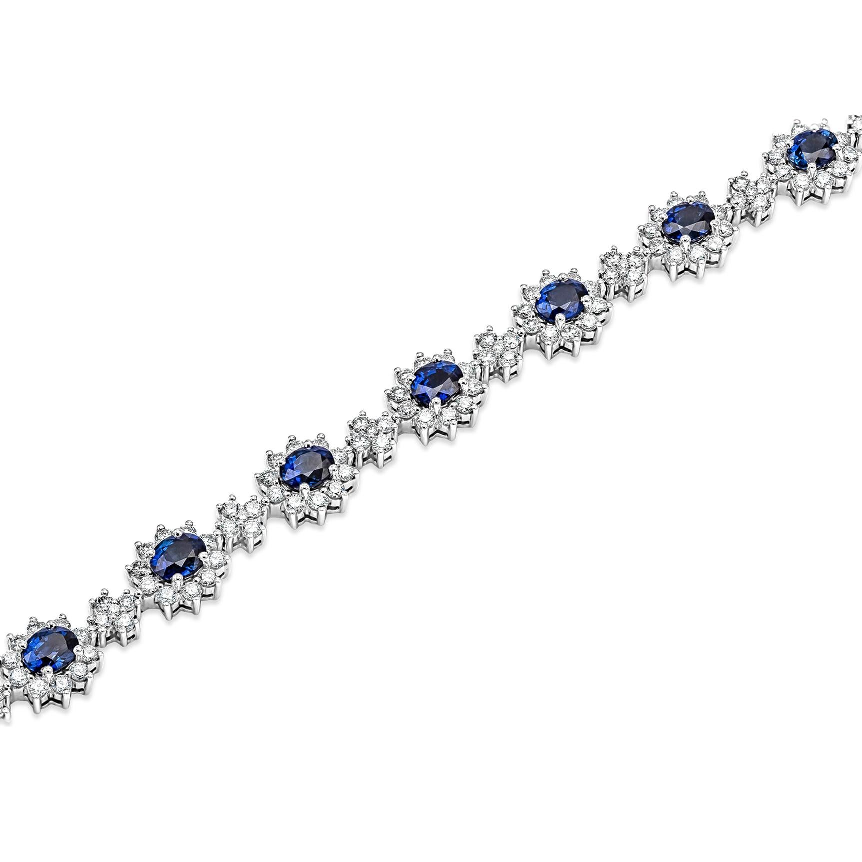 Bringen Sie Farbe in Ihren Stil mit diesem wunderschönen Saphir-Blumenarmband. 12 blaue Saphire im Ovalschliff, umgeben von einer einzigen Reihe funkelnder runder Diamanten in einer Fassung mit floralem Motiv. Zwischen jeder Saphirblüte befindet