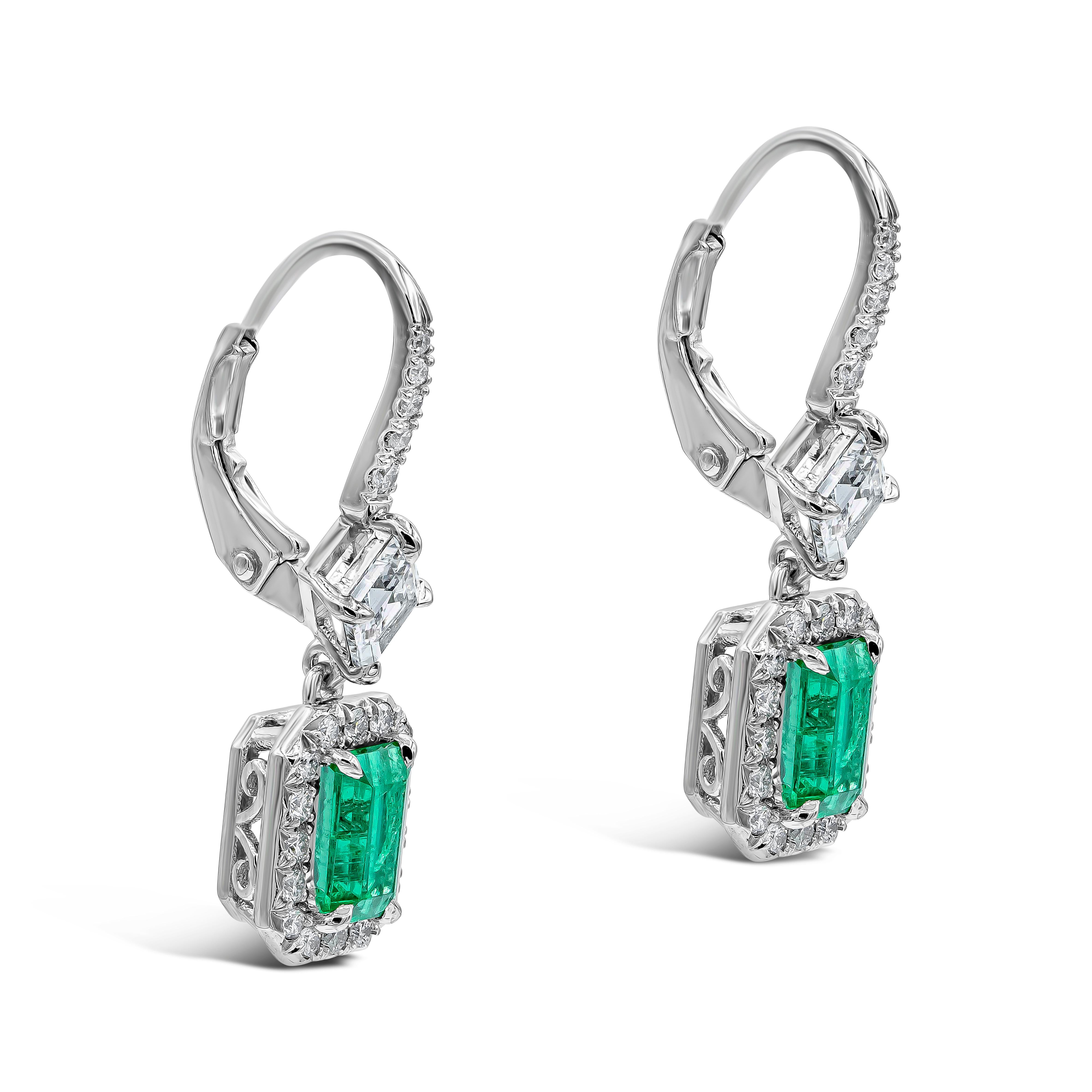 A stunning pair of dangling earrings, showcasing very fine Colombian emeralds of 1.37 carats total, set on platinum. Surrounded by a single row of round brilliant diamonds and suspended on a diamond encrusted lever-back spaced by a beautiful lozenge
