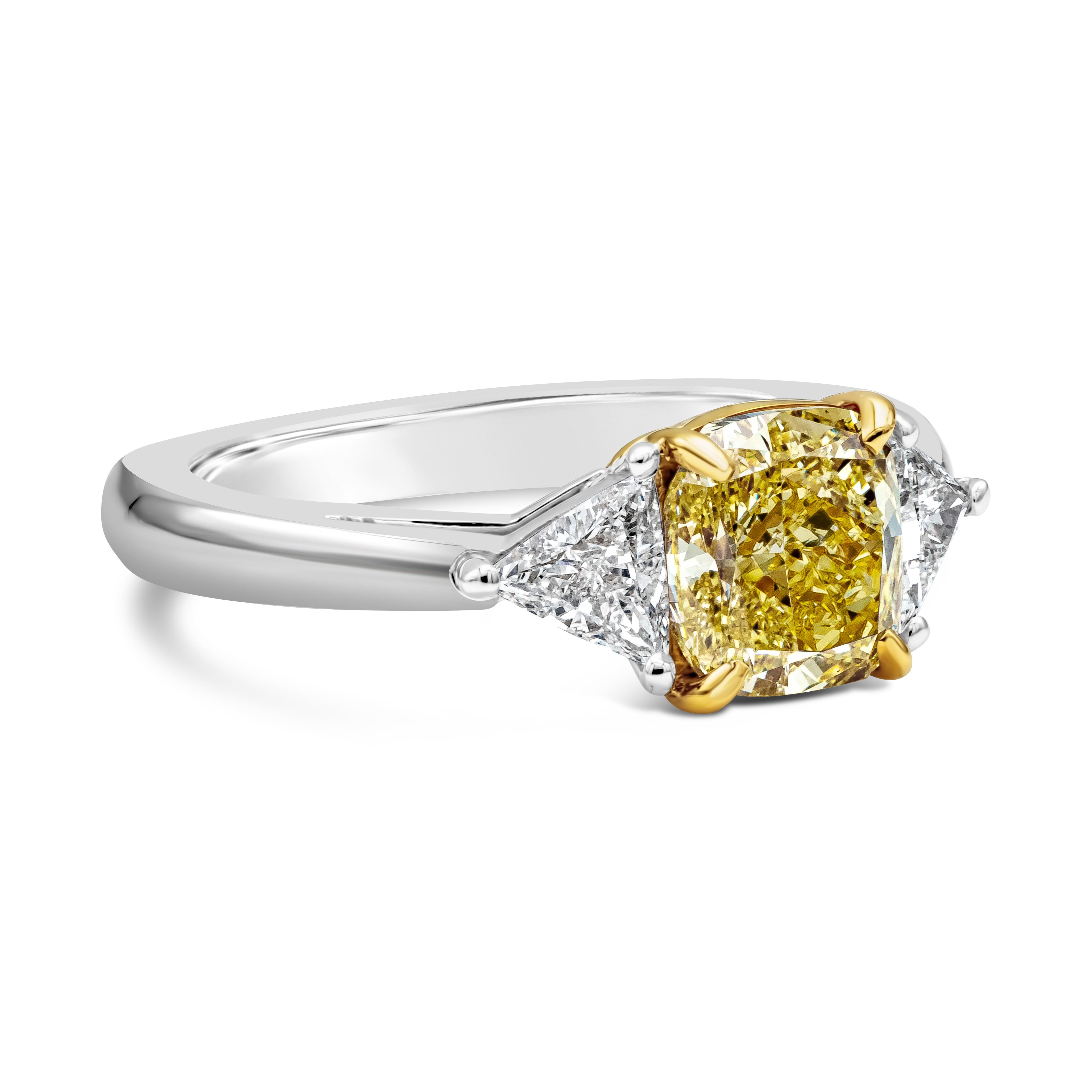 this three stone ring features a 1.65 carat cushion cut diamond center stone that GIA certified as Fancy Intense Yellow Color and SI1 clarity. Trillion side stones flank the center stone and weighs 0.44 carats total. Made in platinum with 18k yellow