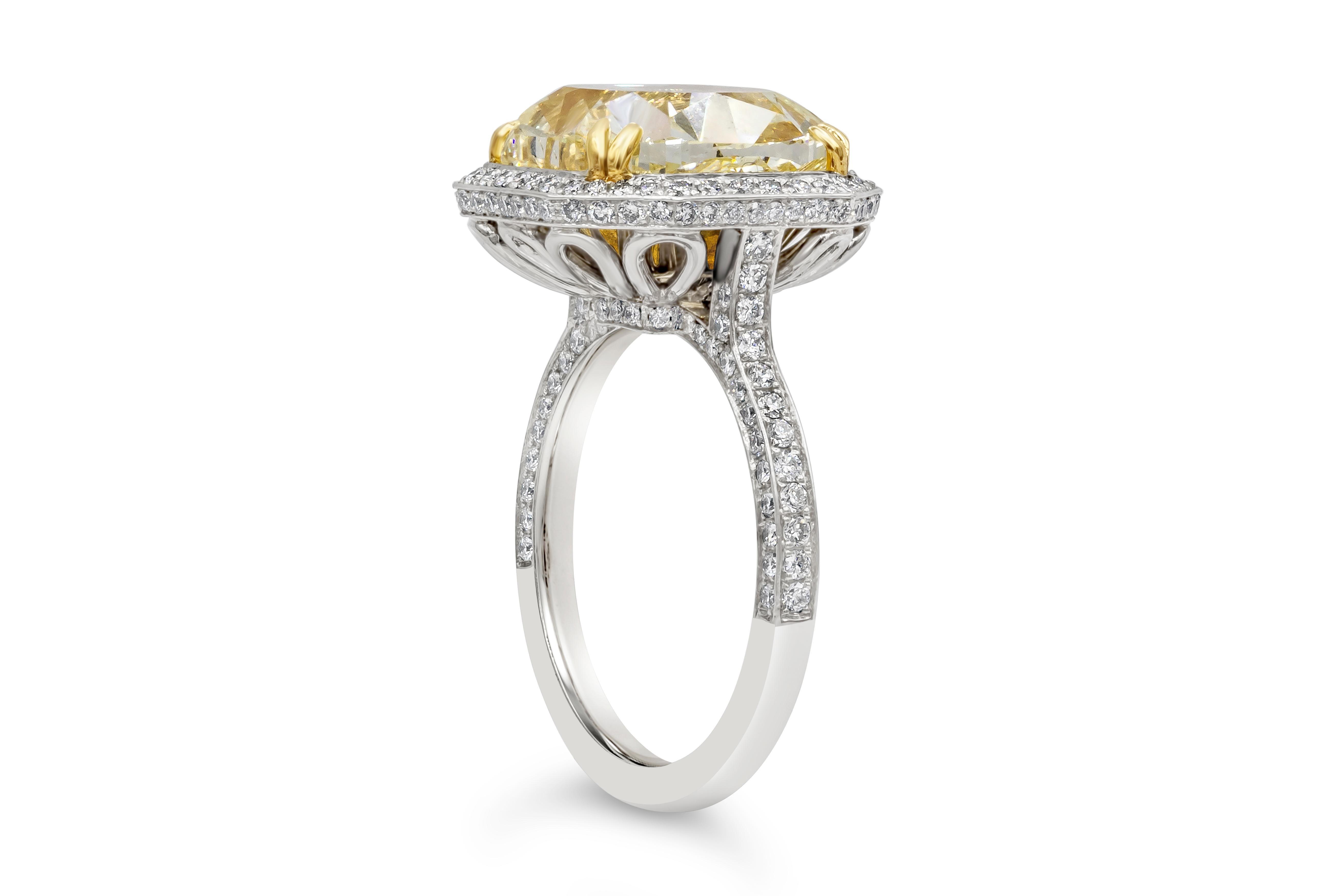 Well crafted color rich halo style engagement ring showcasing a fancy yellow center stone GIA certified 7.64 carat cushion cut, set in an 18k yellow gold eight prong basket. Surrounded by a row of round brilliant diamonds set in a halo design.