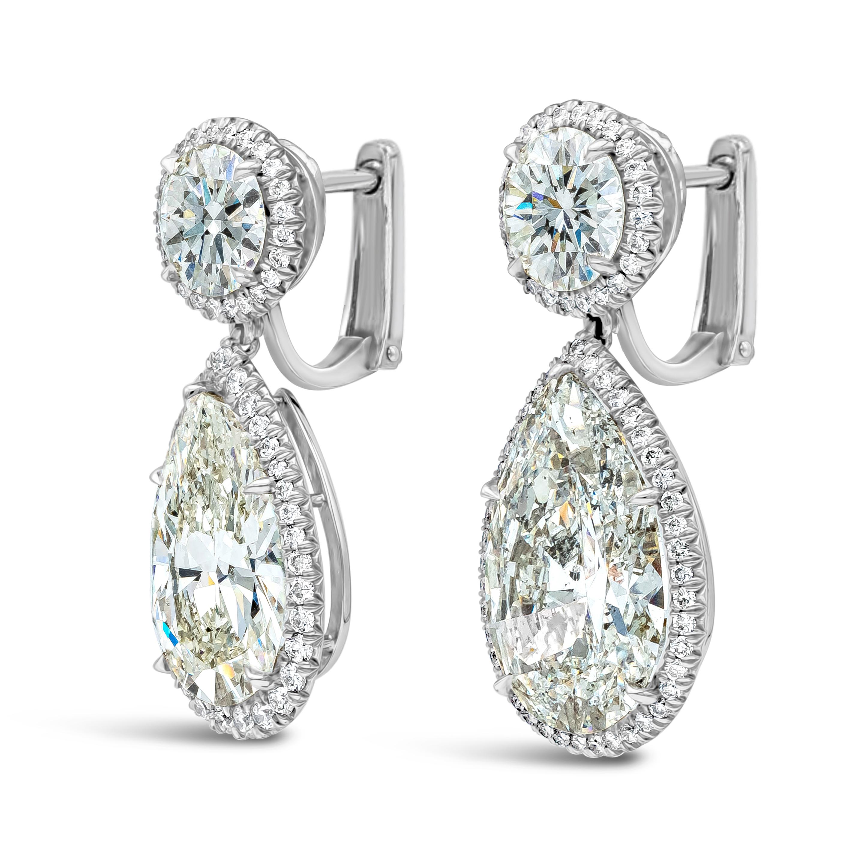 An elegant and well-crafted pair of high end dangle earrings, featuring GIA certified pear shape diamonds suspended on round brilliant cut diamonds. Both stones are set with round melee diamond halos weighing 2.59 carats total. Pear shape diamonds