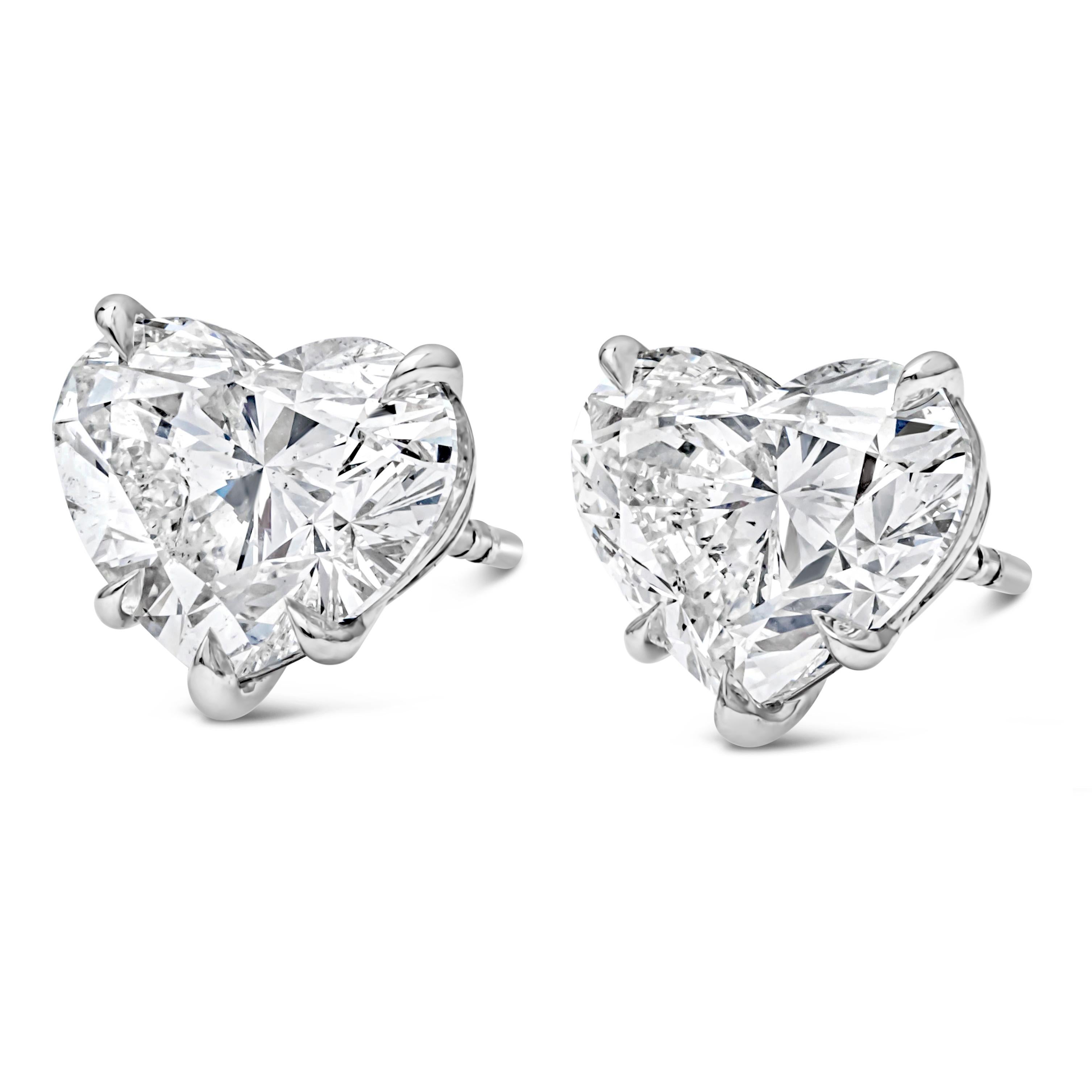 Classic pair of stud earrings, showcasing two GIA certified brilliant heart shape diamonds, weighing 3.01 carats and 3.02 carats with H-I color and SI2 clarity, respectively. Mounted on a timeless five-prong basket setting finely made of