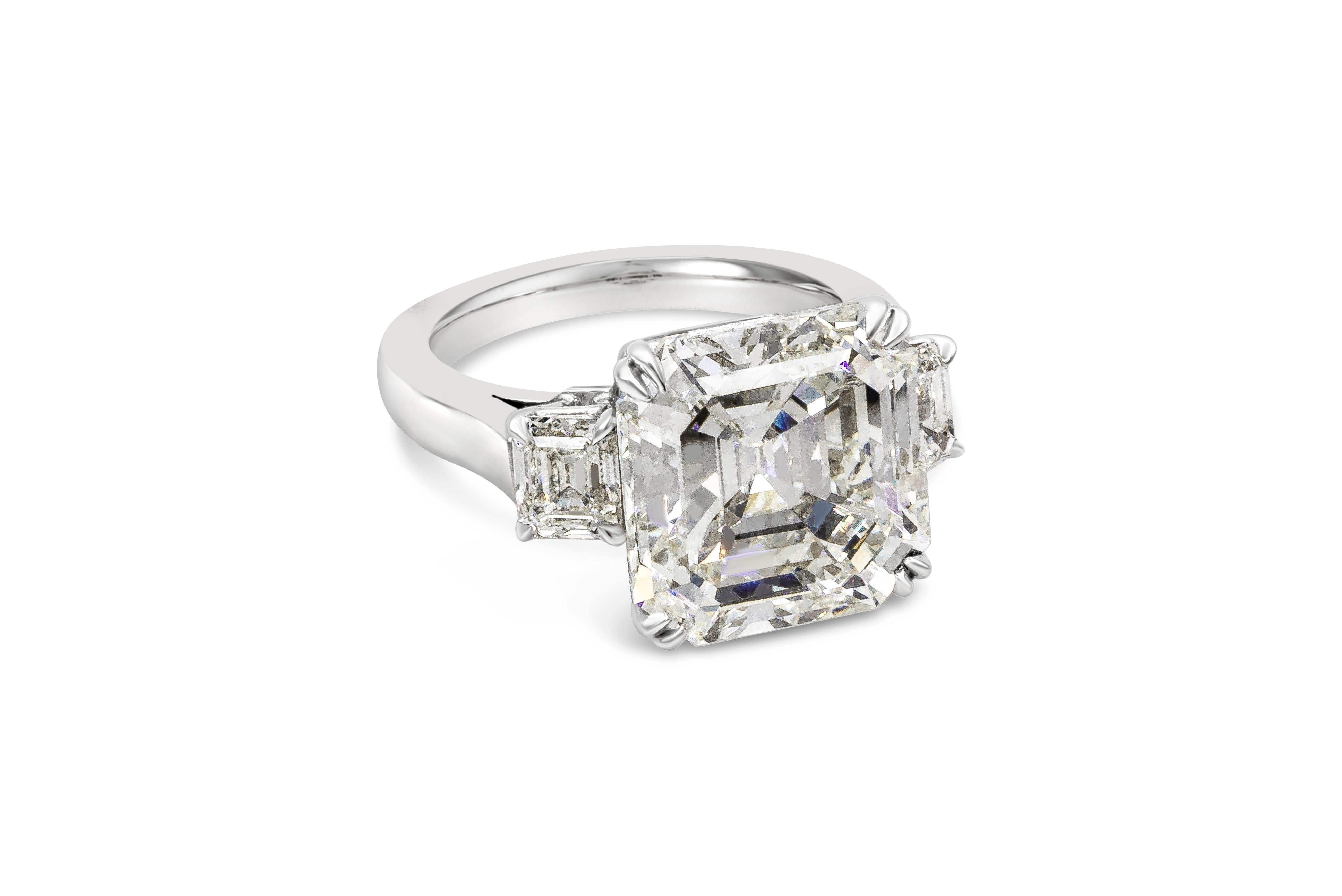 A subtle and sophisticated three stone engagement ring featuring a 9.20 carat asscher cut diamond certified by GIA as J color, VS2 clarity. Flanking the center diamond are 1.15 carats total of emerald cut diamonds set in a polished platinum