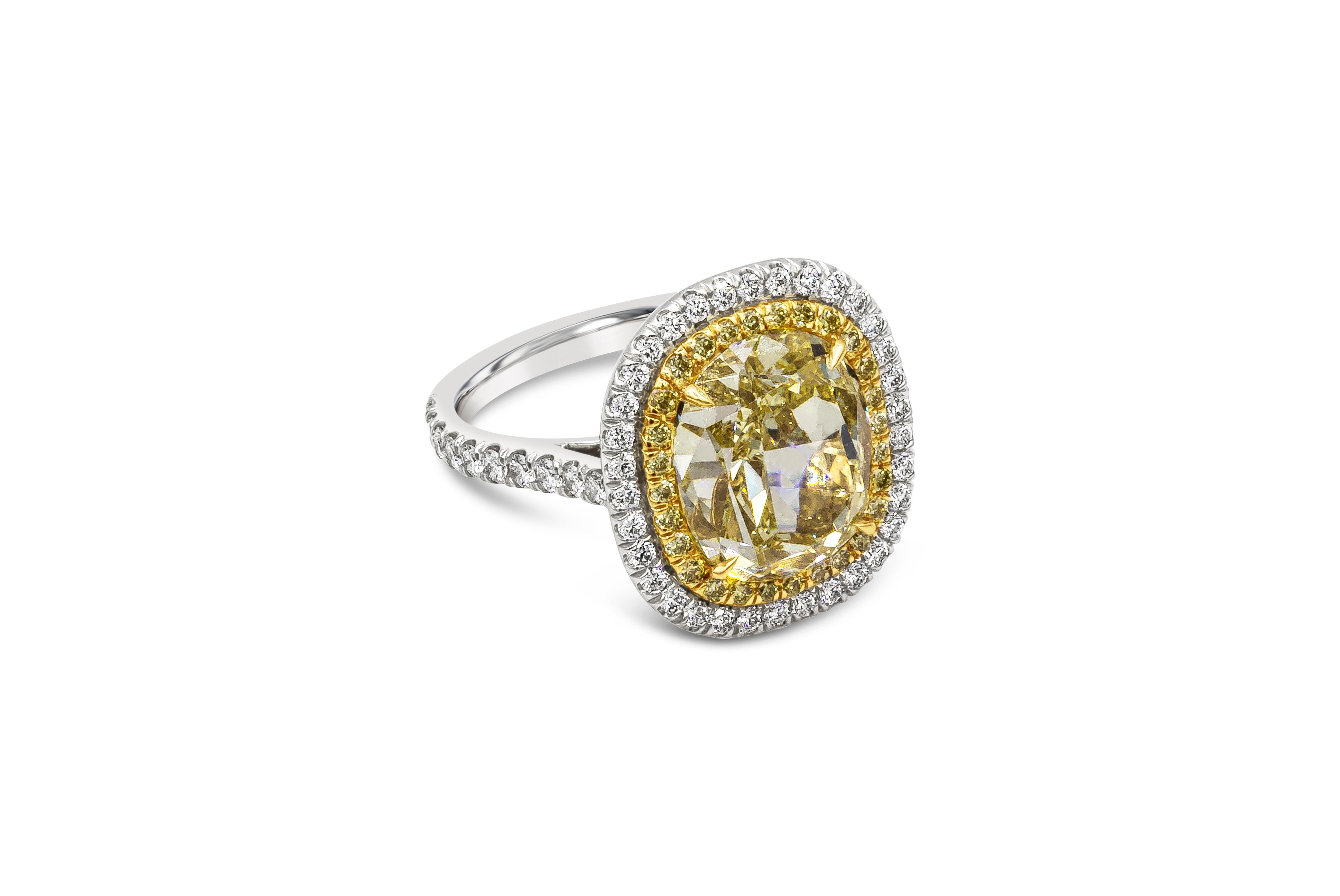Color rich and well crafted halo engagement ring showcasing a vibrant 7.06 carat oval cut diamond set in a four prong 18k yellow gold setting encrusted with 28 brilliant round fancy yellow diamonds weighing 0.25 carats total. Surrounded by a row of