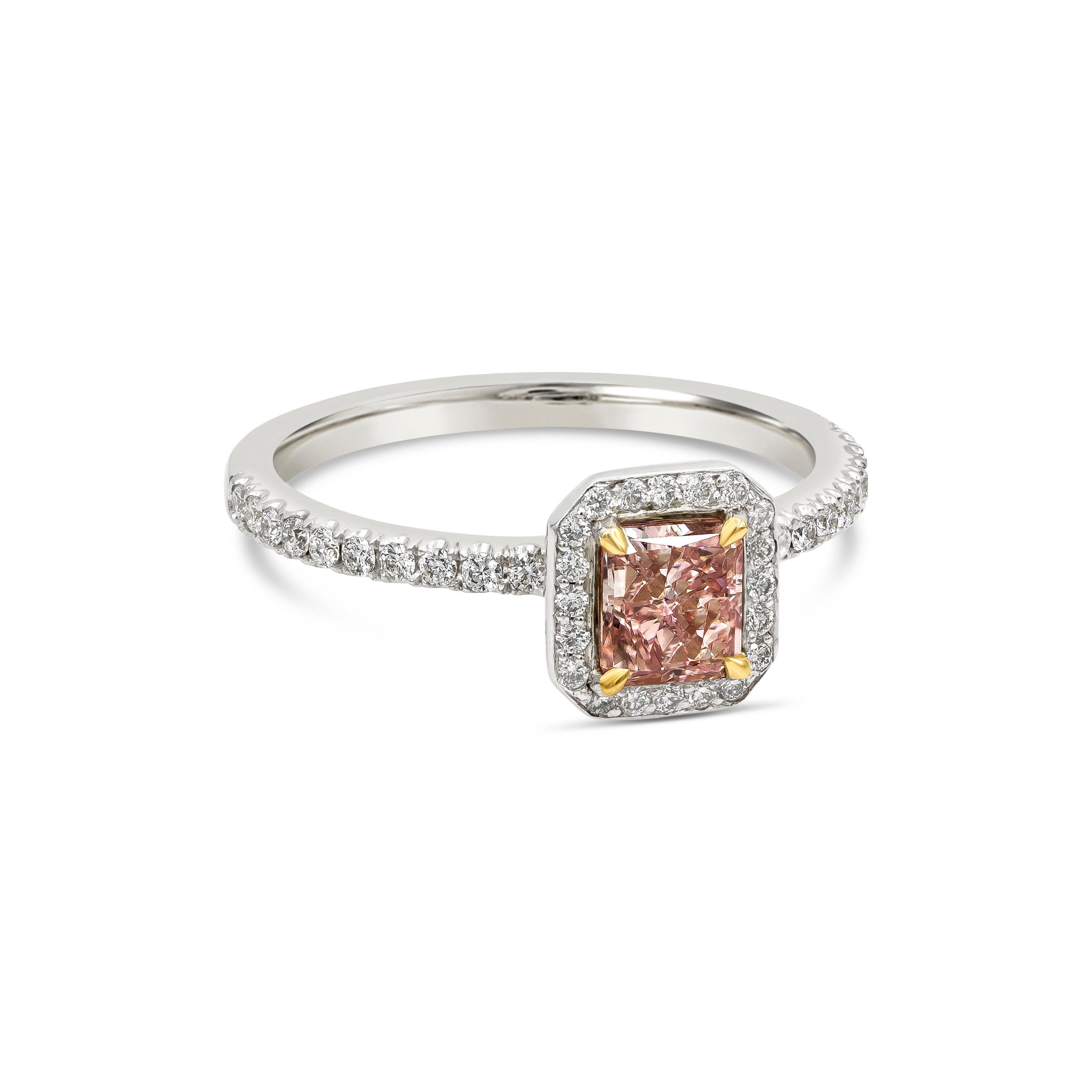 Unique and rare diamond halo engagement ring showcasing a color rich GIA certified 0.73 carats cushion cut fancy orangy pink diamond, VS1 in clarity set in a four prong 18k yellow gold setting. Surrounding the center stone is a row of round