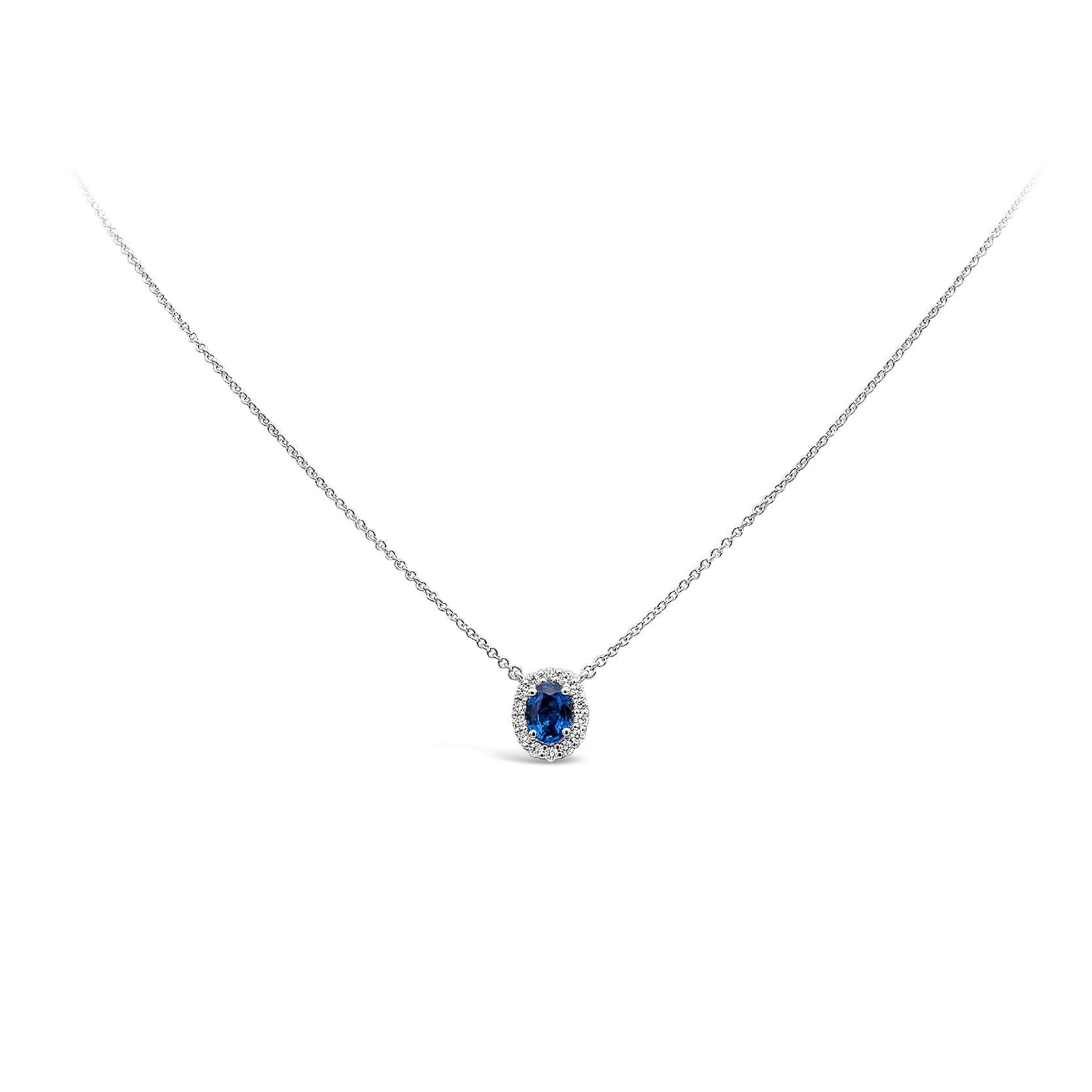 A simple and timeless piece of jewelry showcasing a 0.73 carat oval cut blue sapphire, surrounding by a single row of brilliant round diamonds weighing 0.23 carats total, G color and SI1 in clarity. Suspended on a 18 inches adjustable white gold