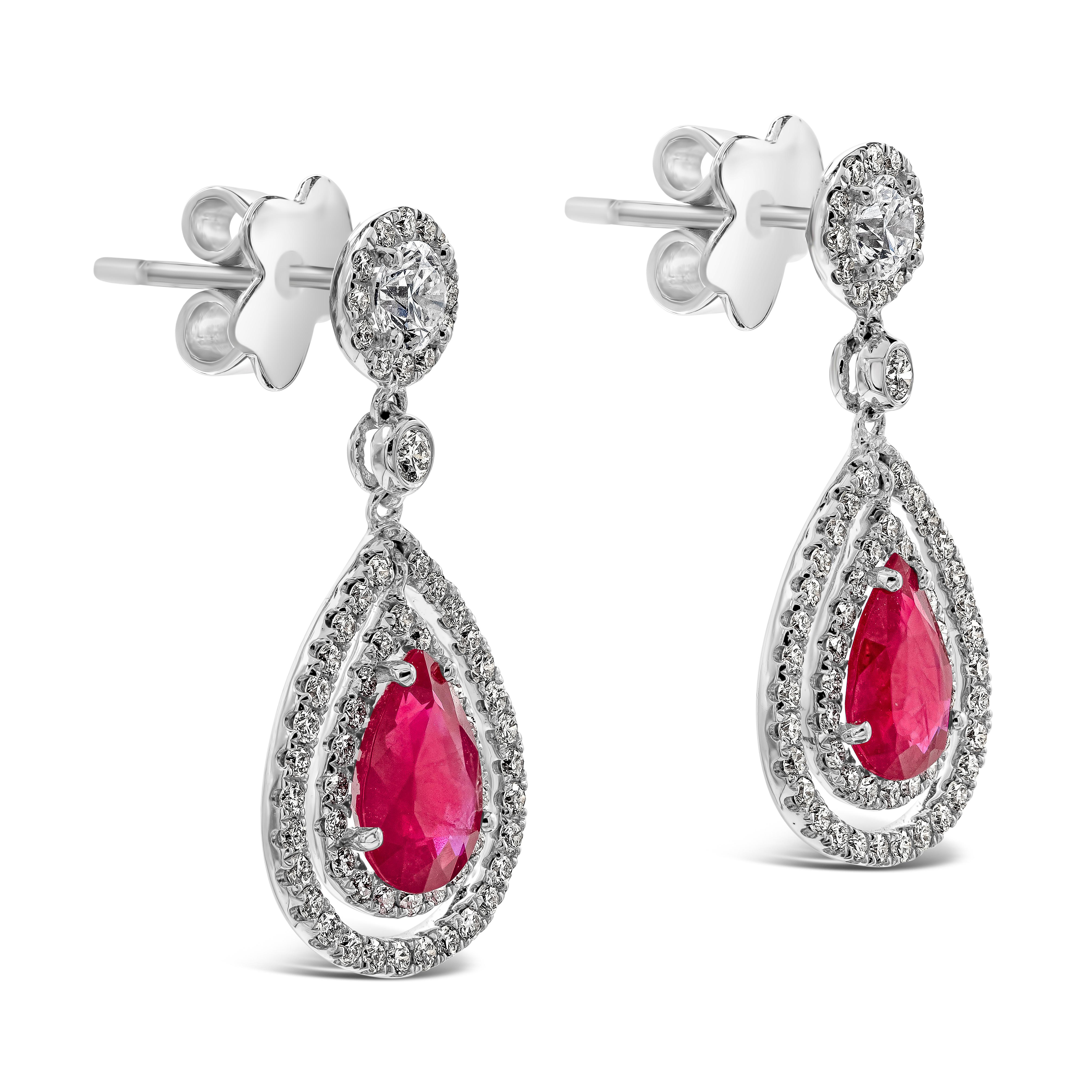 These dangle earrings are set with natural pear shape rubies weighing 2.20 carats total. Each ruby is surrounded by double halo of round brilliant melee diamonds. The jump ring and upper dangle is diamond encrusted in halo setting. Accent diamonds