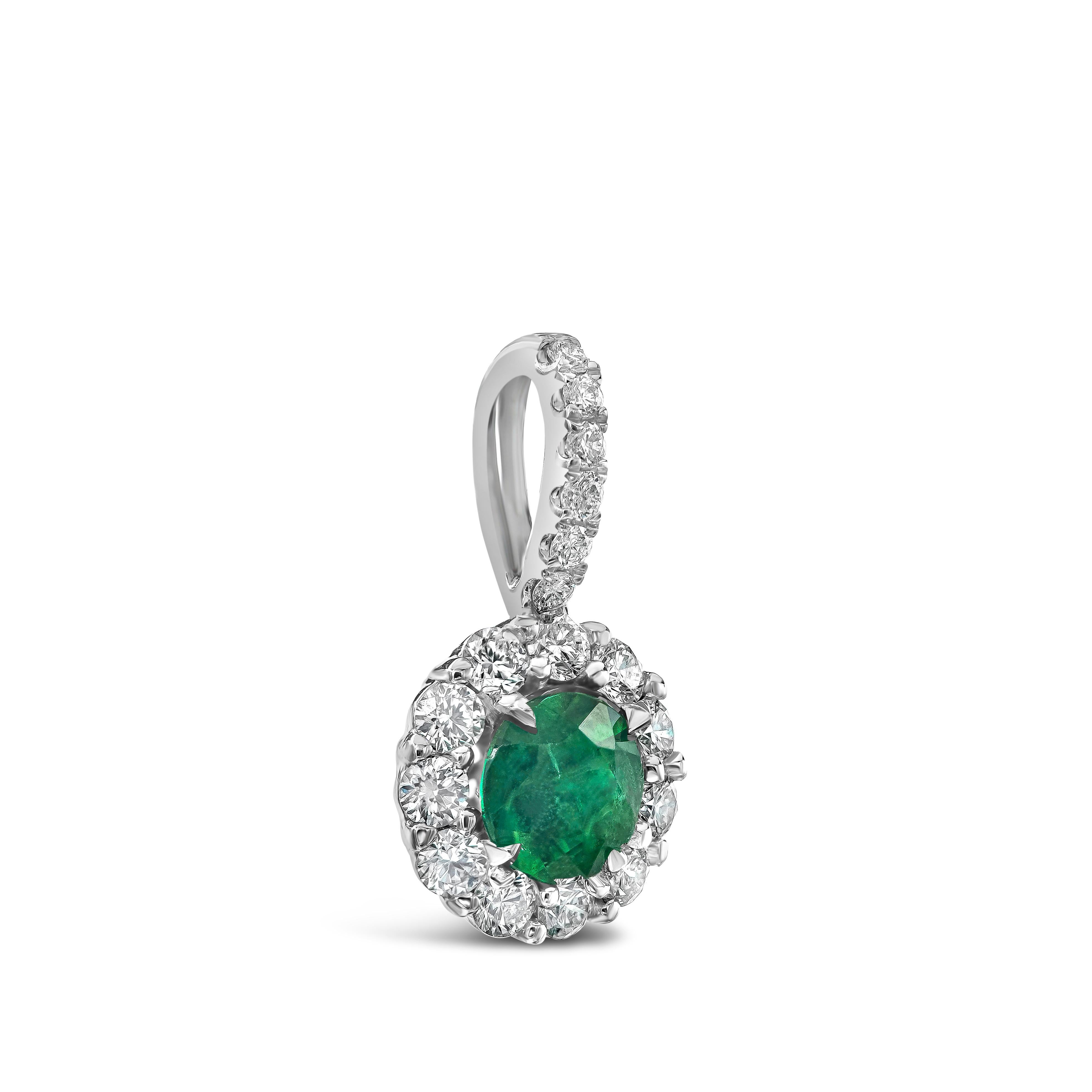 A simple and versatile pendant necklace showcasing a 0.33 carat round green emerald, surrounded by a single row of round brilliant diamonds. Suspended on a diamond encrusted bale, in an 18 inch white gold chain. Diamonds weigh 0.25 carats total.