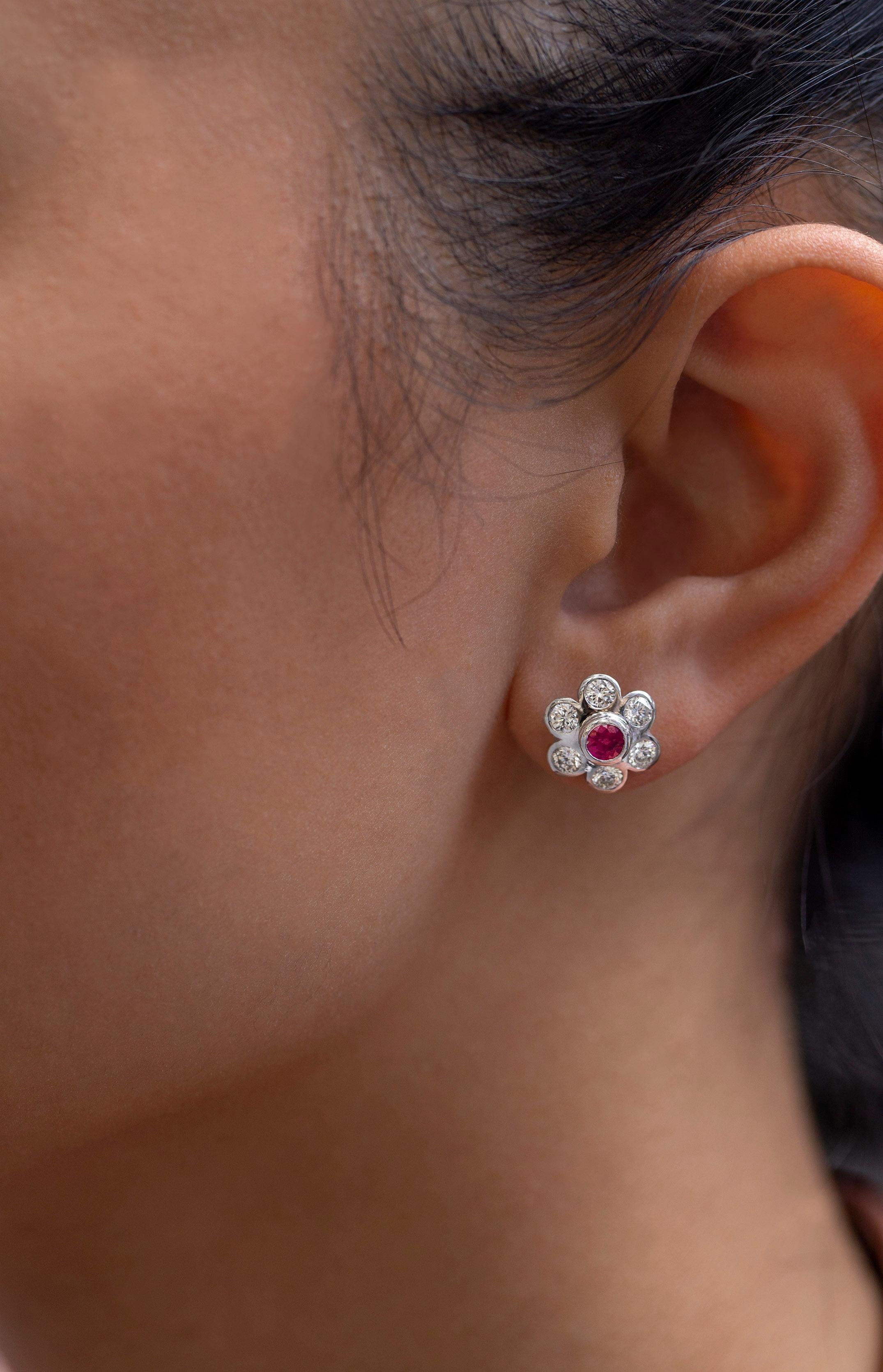 A floral motif stud earrings showcasing a round ruby center, surrounded by round brilliant diamonds. Each stone bezel set in 18 karat white gold. Rubies weigh 0.89 carats total; diamonds weigh 1.18 carats total.

Style available in different price