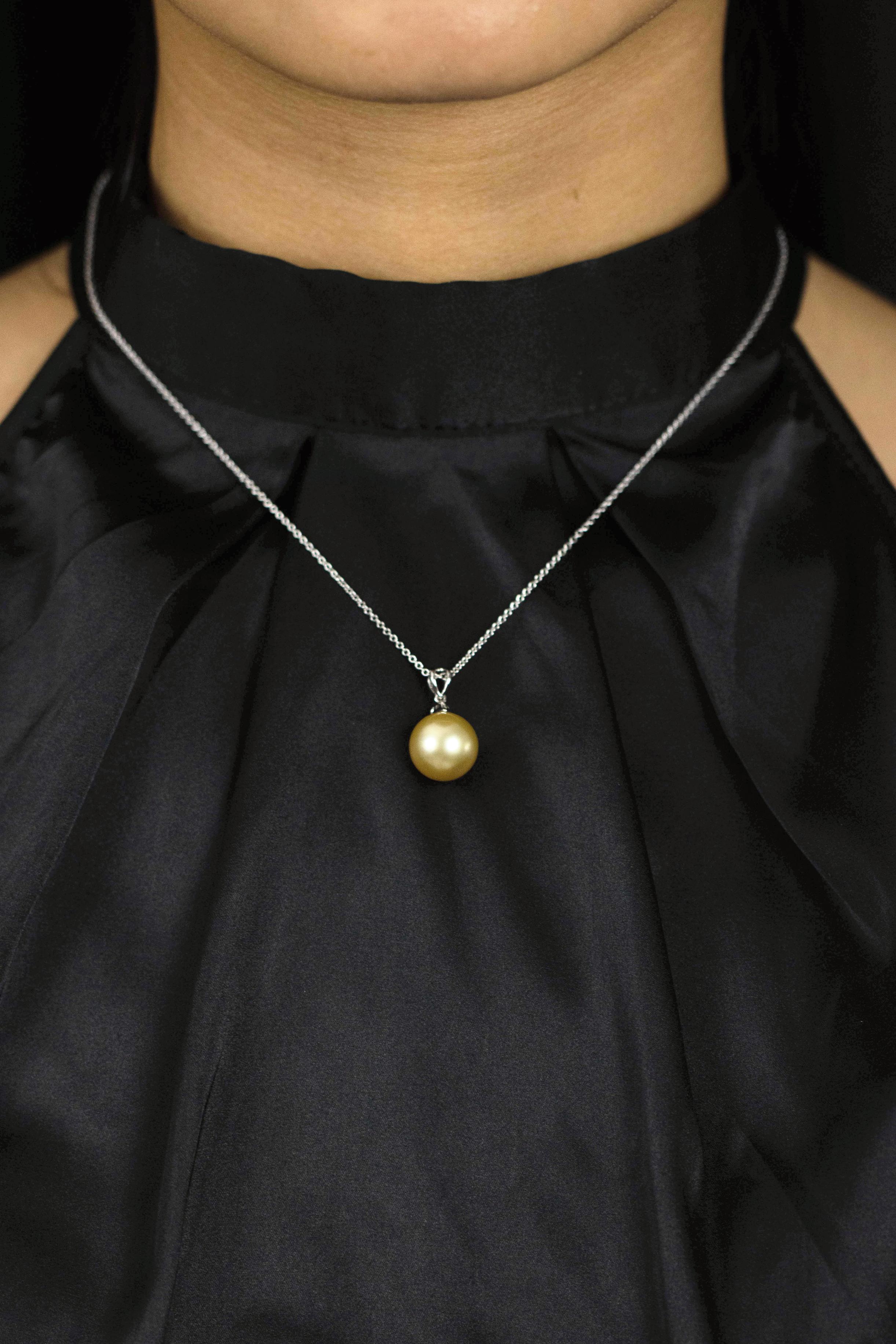 This beautiful pearl necklace showcasing an 12 millimeter south sea pearl of golden color. Accented with a single round diamond weighing 0.16 carats. Suspended on an 18 inch adjustable white gold chain.

Style available with matching earrings.