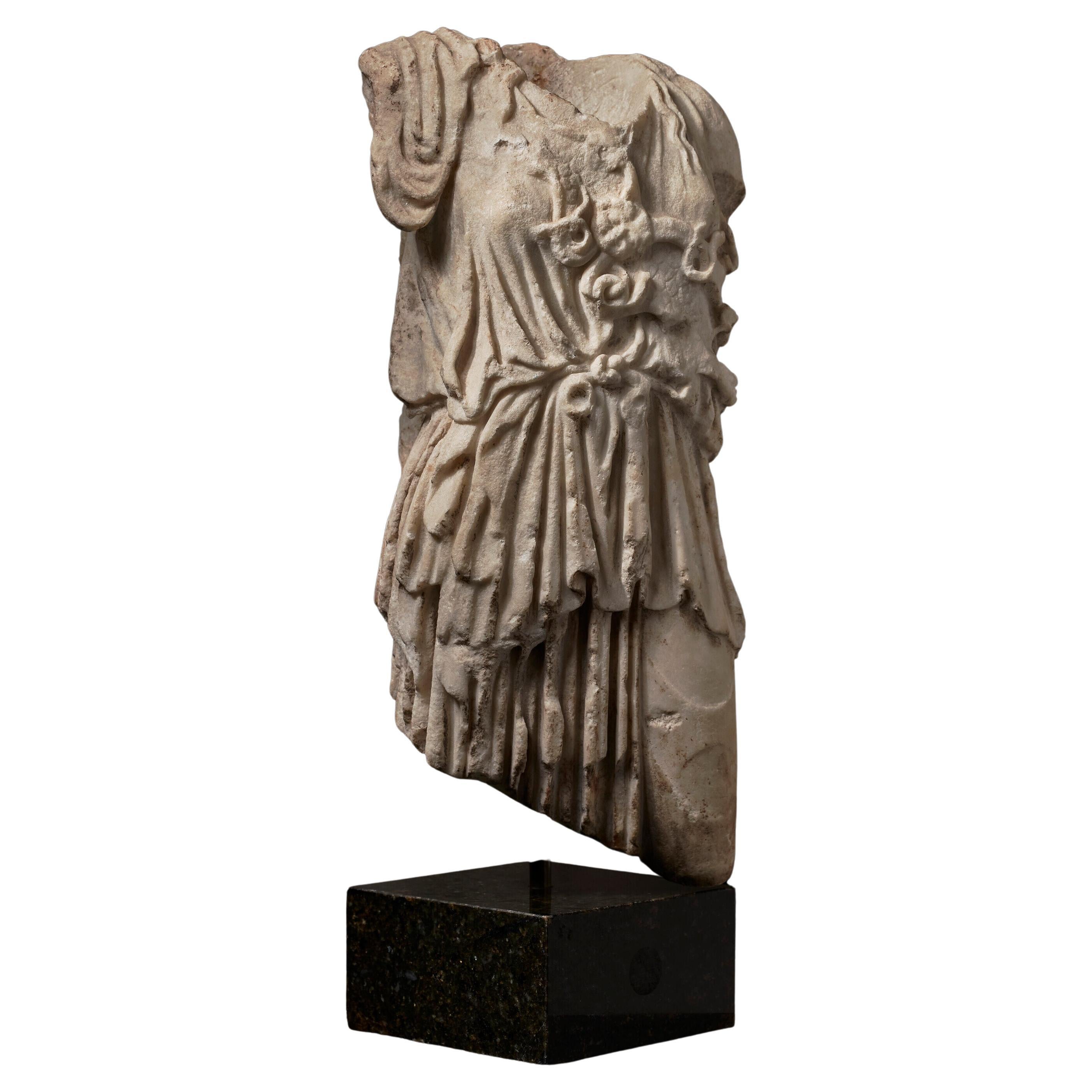 This Roman marble torso of Athena captures the timeless strength and grace of the goddess of wisdom and war. With finely carved details suggesting the remnants of a flowing chiton, this piece conveys both power and elegance. Crafted from quality