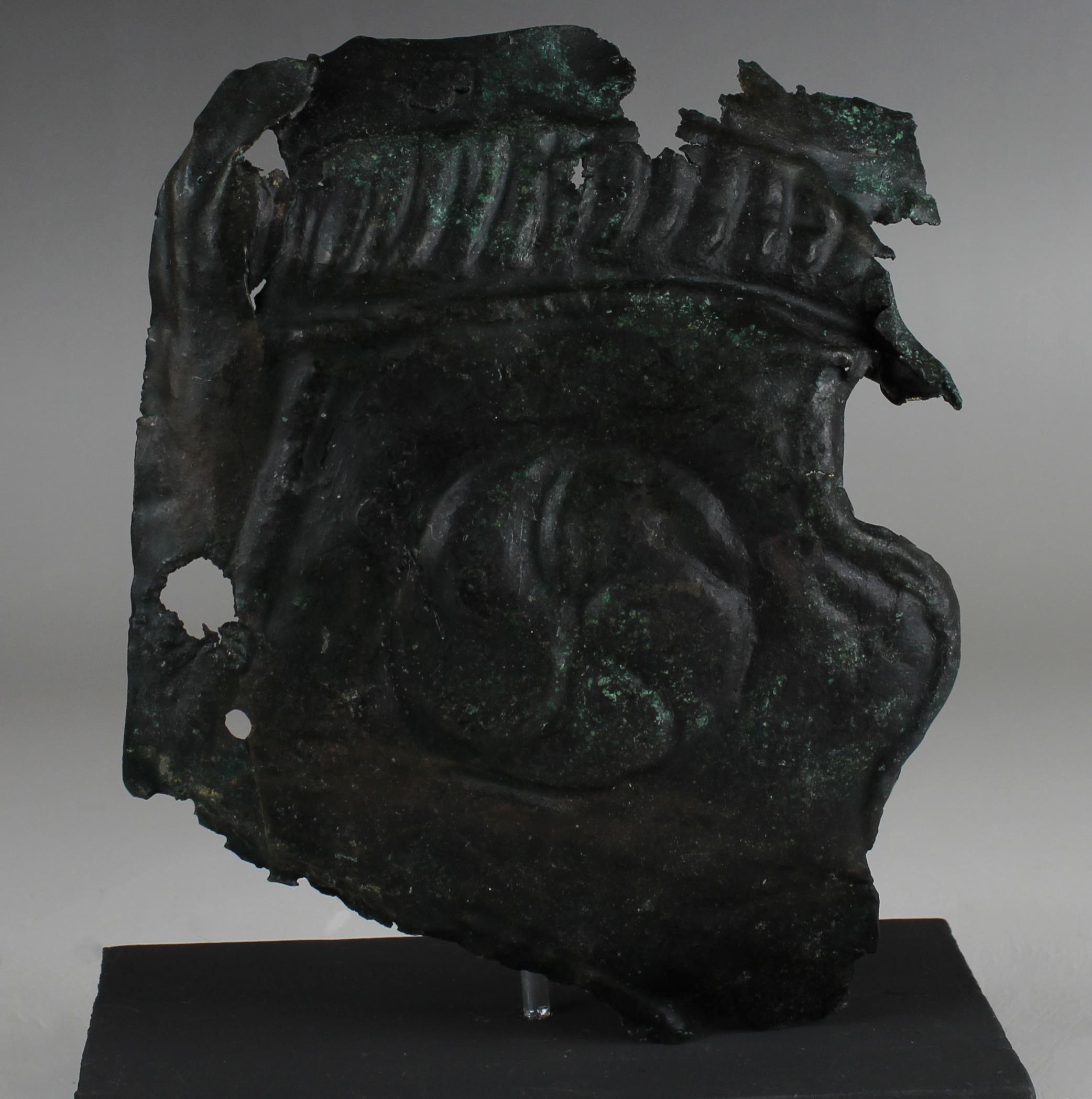 ITEM: Military cheek piece of a helmet fragment with shield ornament
MATERIAL: Bronze
CULTURE: Roman
PERIOD: 3rd Century A.D
DIMENSIONS: 130 mm x 110 mm
CONDITION: Good condition
PROVENANCE: Ex Alison Barker private collection, a retired London
