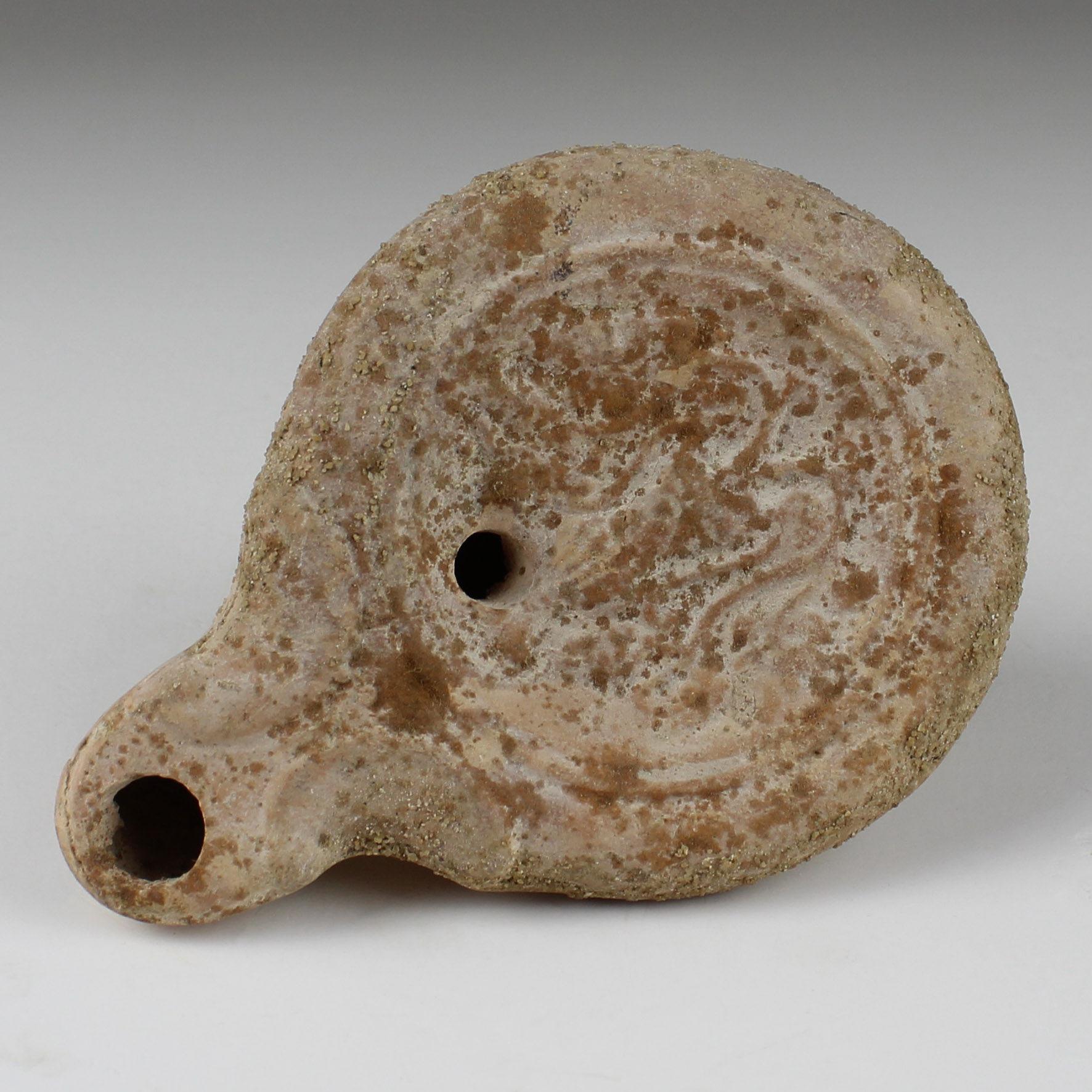 ITEM: Oil lamp with leaves and fruit, Type Bussiere B III 1
MATERIAL: Terracotta
CULTURE: Roman
PERIOD: 1st – 2nd Century A.D
DIMENSIONS: 20 mm x 65 mm x 90 mm
CONDITION: Good condition
PROVENANCE: Ex Emeritus collection (USA), collected from the