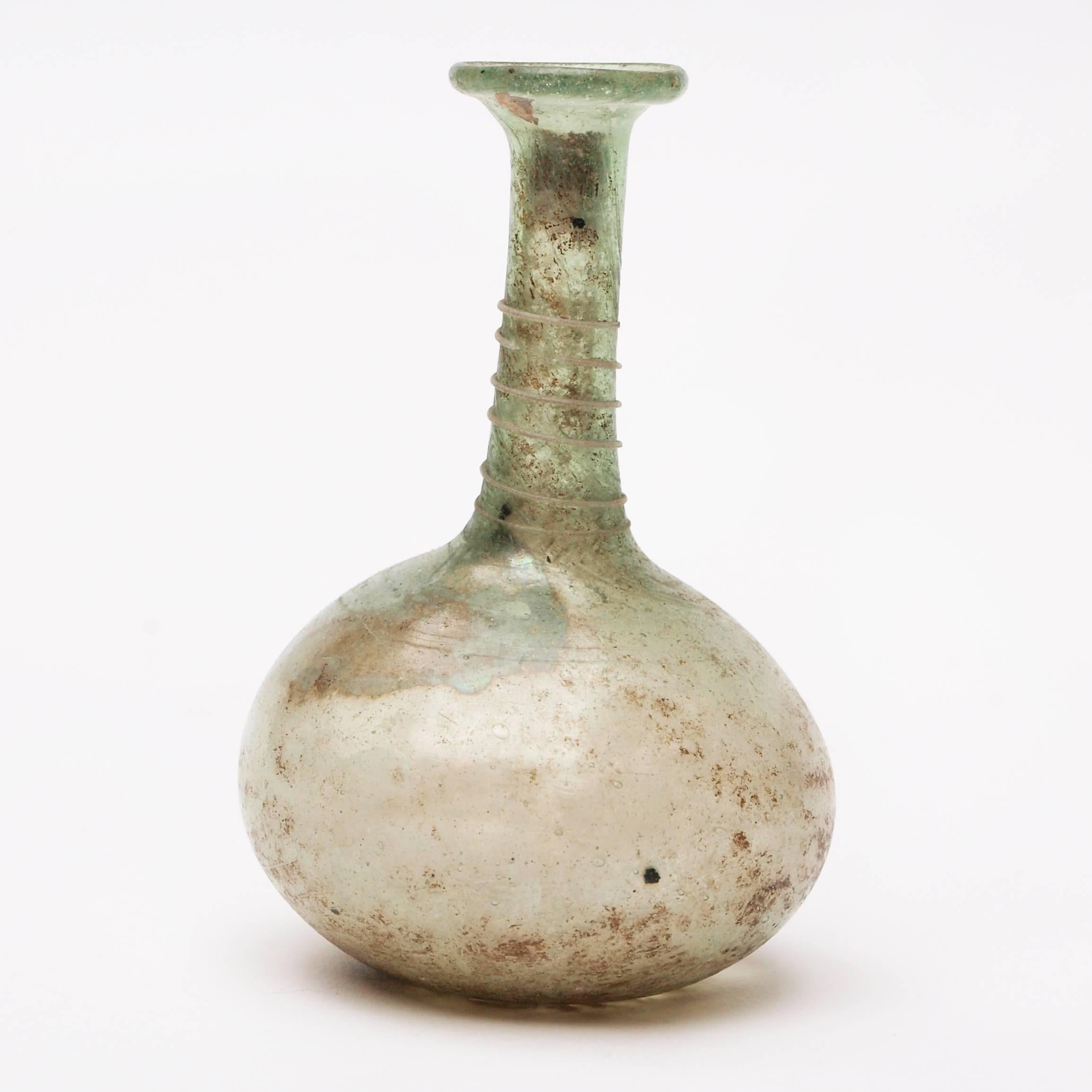 A handblown Roman pale green and white flask dating from the 2nd-3rd century decorated on the neck with a spiralled thread.