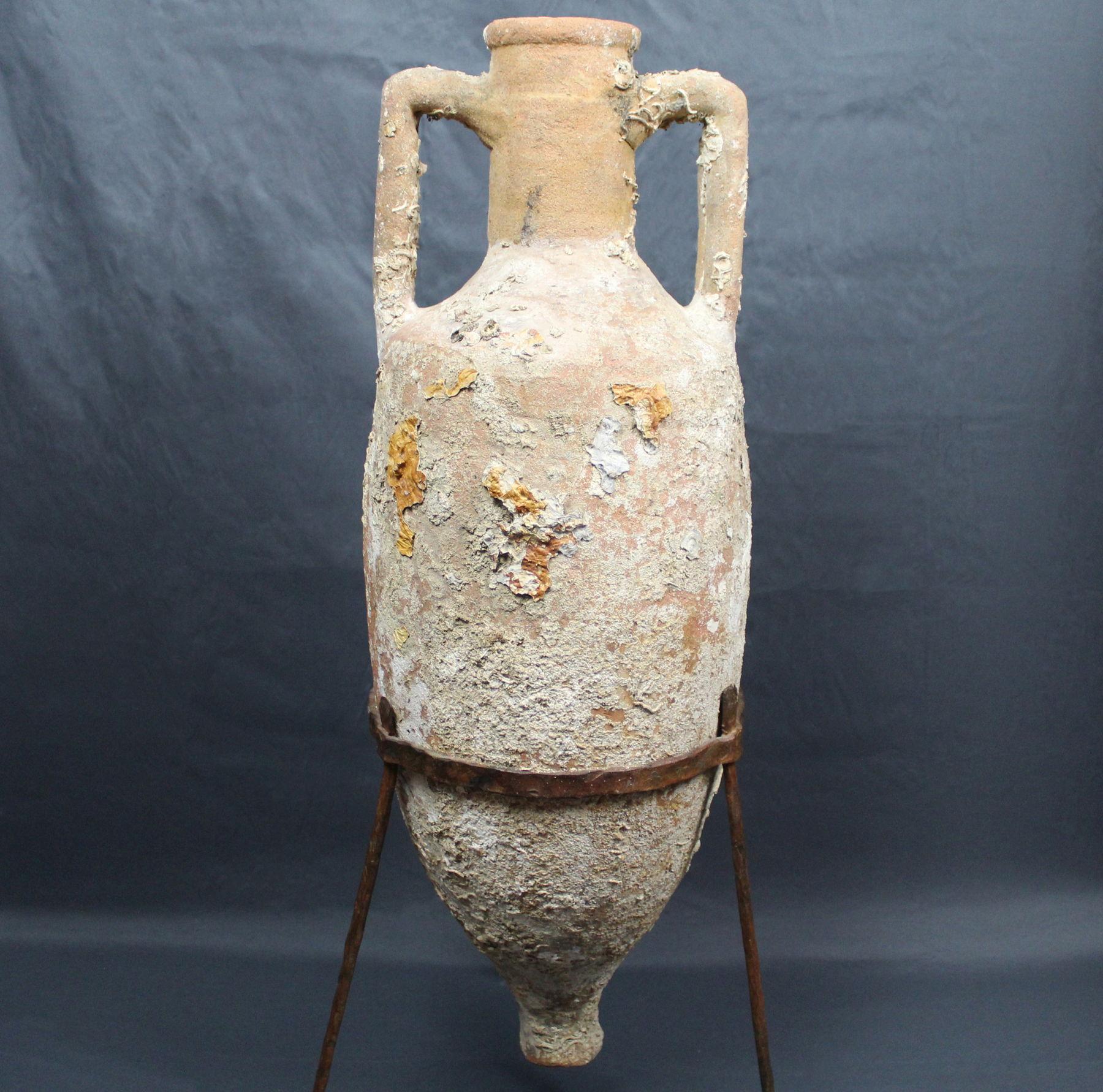 ITEM: Shipwreck amphora, Type Dressel 3
MATERIAL: Pottery
CULTURE: Roman
PERIOD: 1st – 2nd Century A.D
DIMENSIONS: 84 cm x 26 cm diameter (without stand), 90 cm x 26 cm diameter (with stand)
CONDITION: Good condition. Small missing part in the
