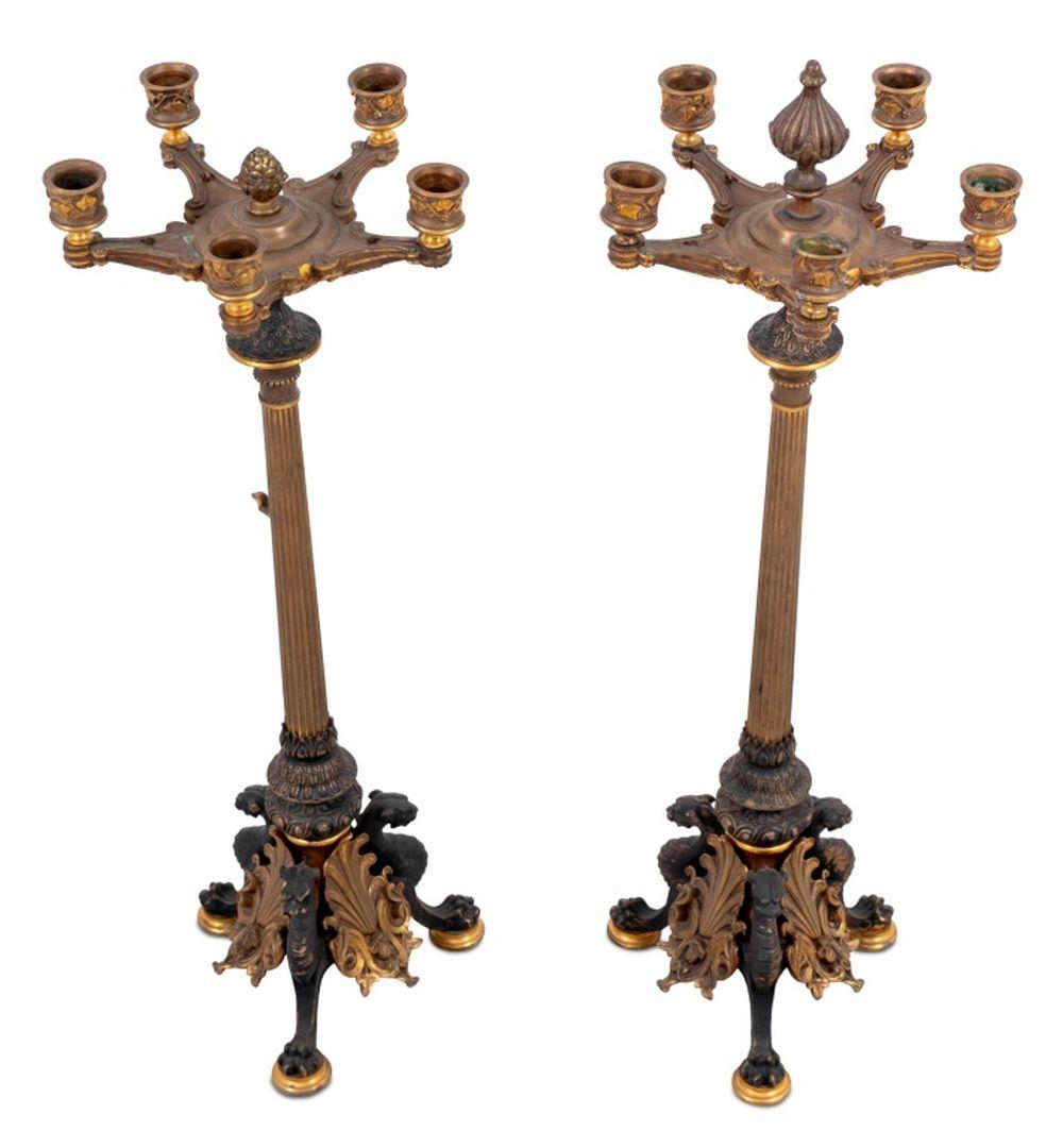 Paire de candélabres en bronze patiné et doré de style romain, fin du XIXe siècle, d'après l'antique, chacun à cinq branches surmontant des colonnes fuselées cannelées reposant sur des pieds monopodes en forme de griffon. 24.5