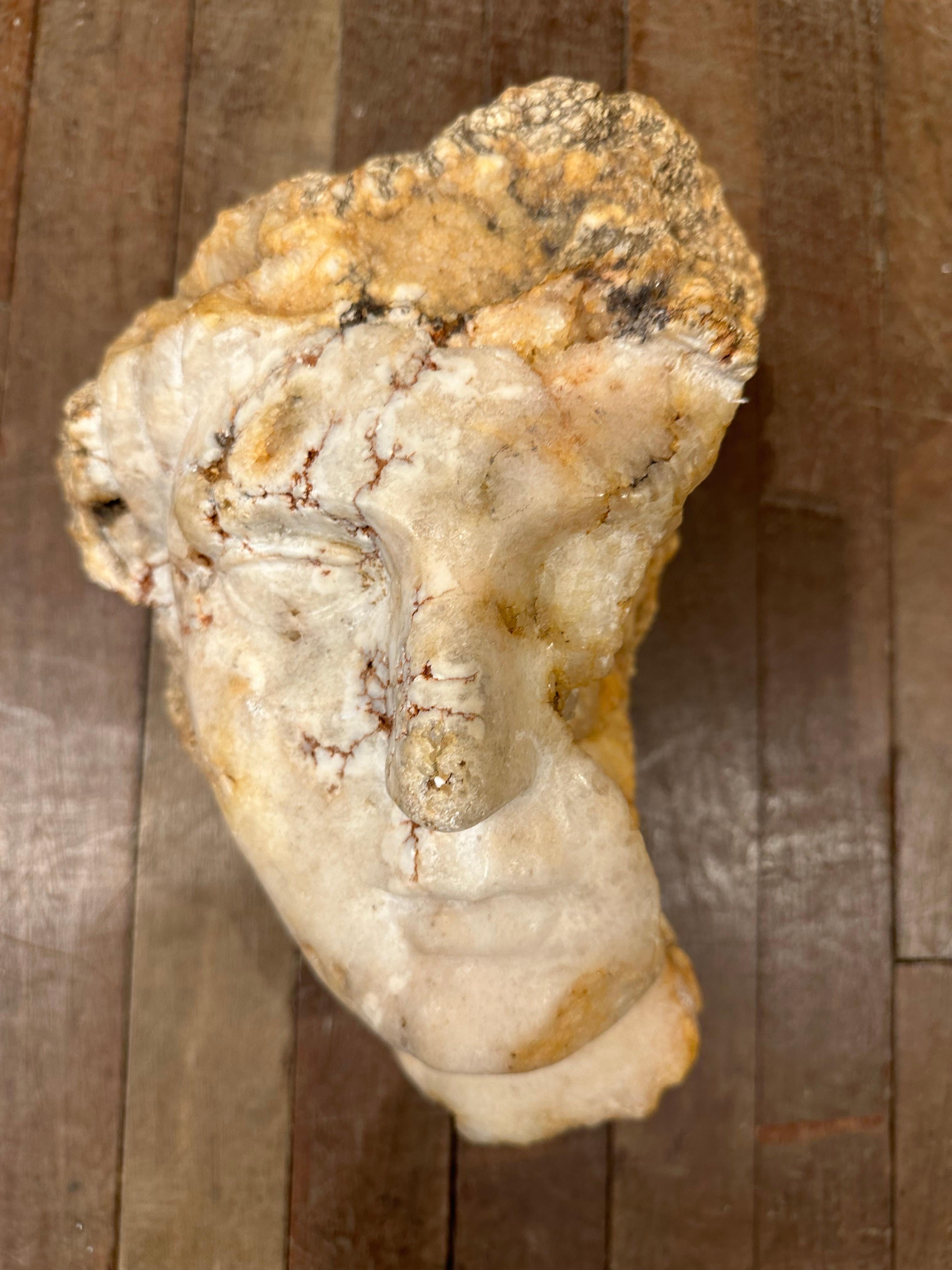 A richly weathered marble Roman style head with skilfully carved features and full lips. The piece would have been part of a larger statue or carving. The marble has a lovely warm patina, its texture in contrast to the smoothness of the facial