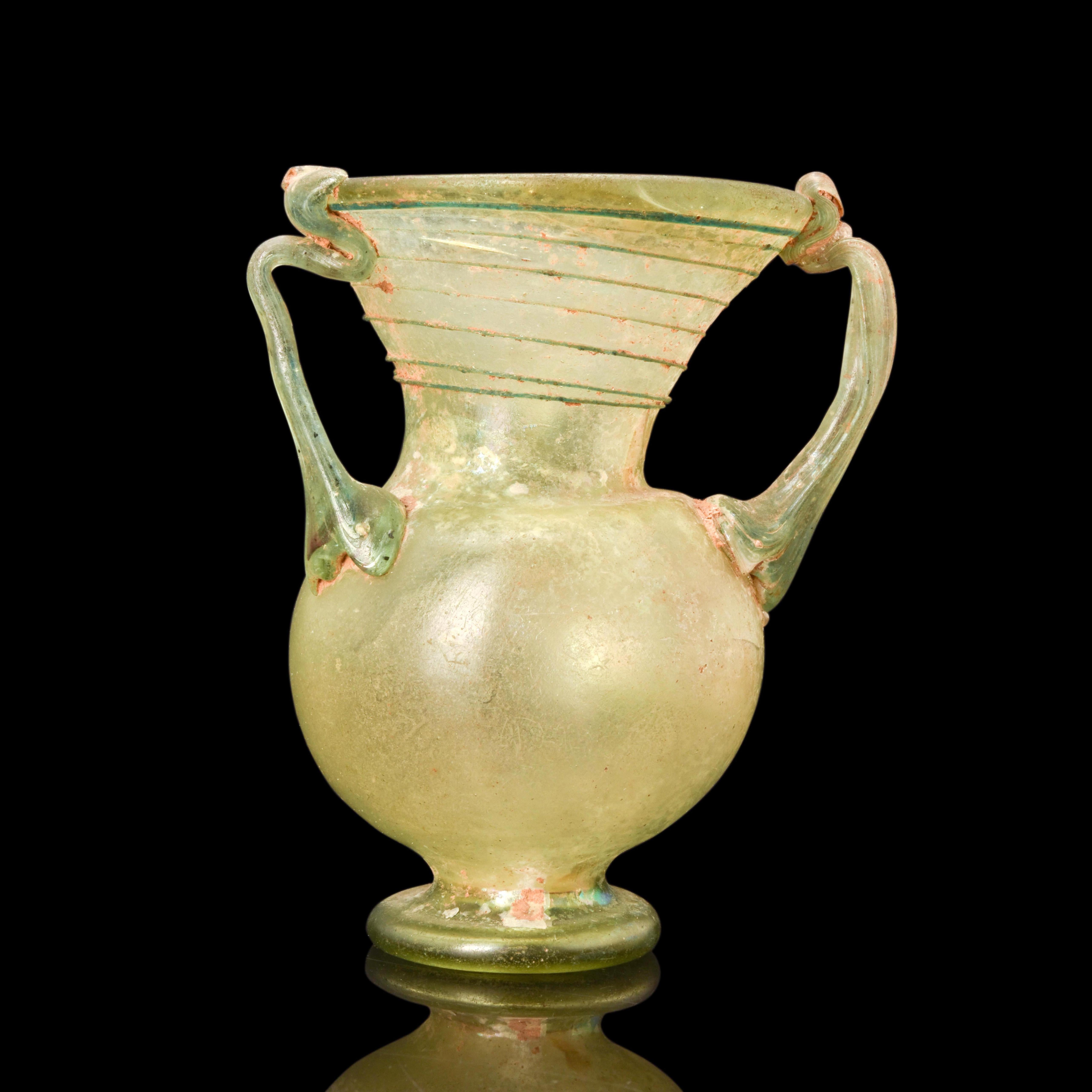 A Roman three-handled jar, blown from greenish-yellow glass. The handles and trail of the jar are rendered in a darker tint. The jar is rounded with a slightly inverted rim and wide flaring mouth tapering into the shoulder. It has a slightly