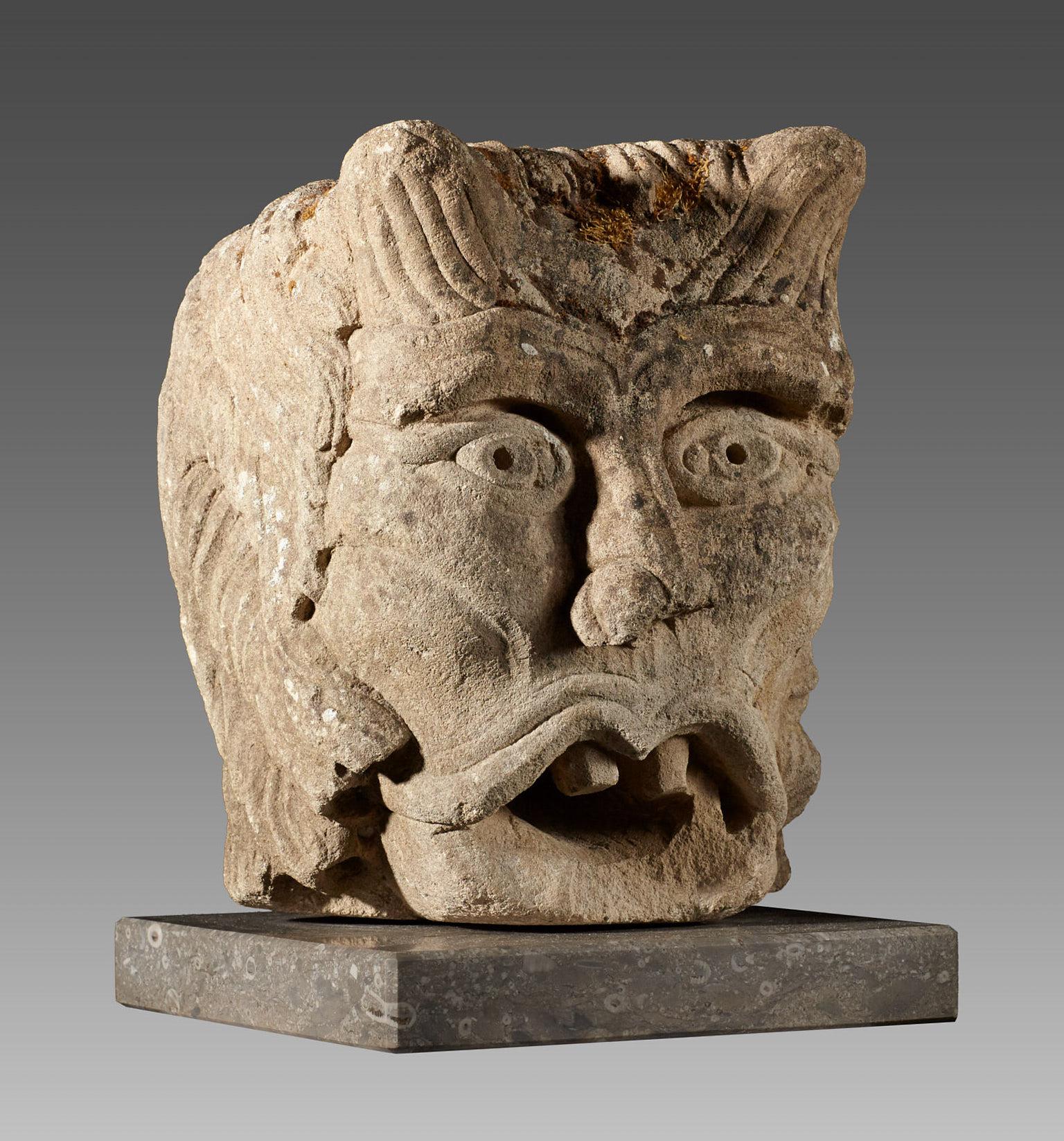 Rare Romanesque green man water spout, Anglo Norman, circa 1150.

The relief carved Caen stone green man head with boldly detailed eyes and gaping toothed mouth. With foliate decoration to the head ears and sides. 

A virtually identical water