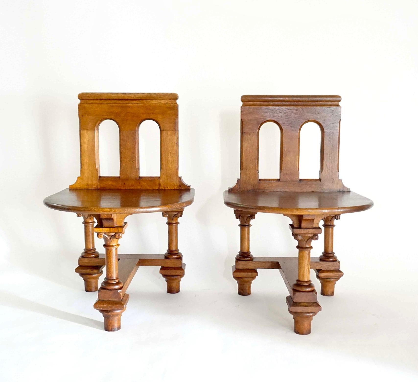 A highly unusual pair of late 19th/early 20th century French Norman Romanesque Revival hall seats or chairs of architectural form and solid oak construction having double arch carved backs above deep D-form seats supported by bracketed T-form