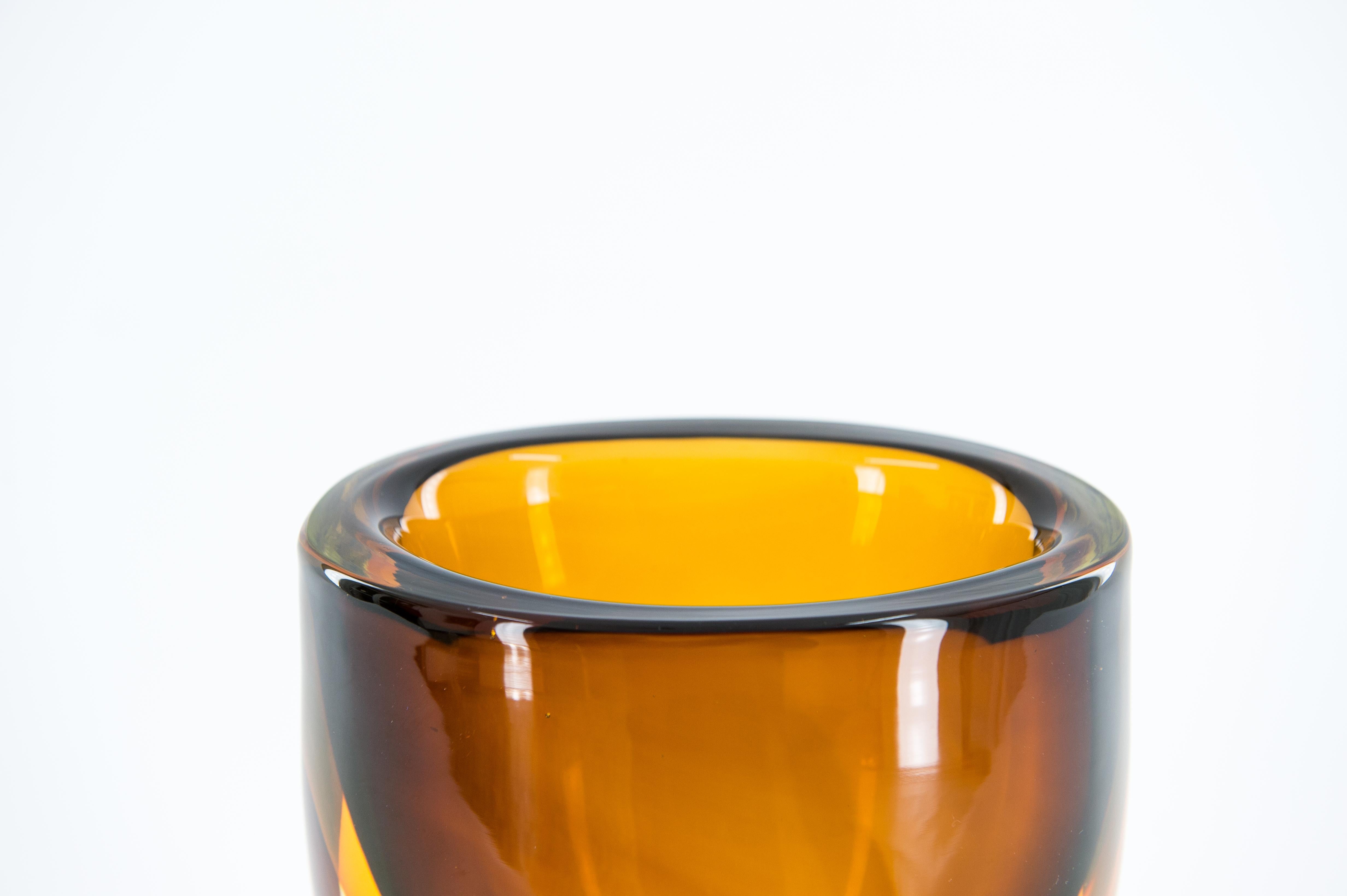 This captivating Murano art glass vase, designed by the renowned Romano Donà in the 1980s, is a stunning example of the Sommerso cased glass technique. Its rich amber and clear glass layers create a dynamic, sculptural form that makes it a true