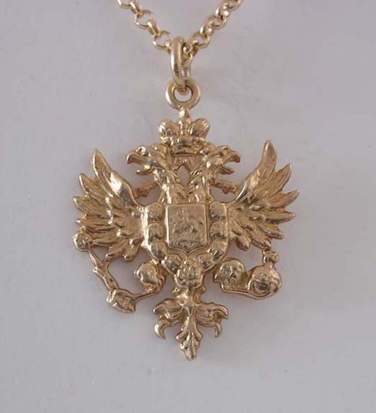 The Romanov double-headed eagle of vermeil or gilded silver with splayed wings, its claws clutching orb and sceptre, surmounted by an imperial crown, the reverse with a smooth polished finish. Chain not included.

1 1/8 in. (2.9 cm.) long, including