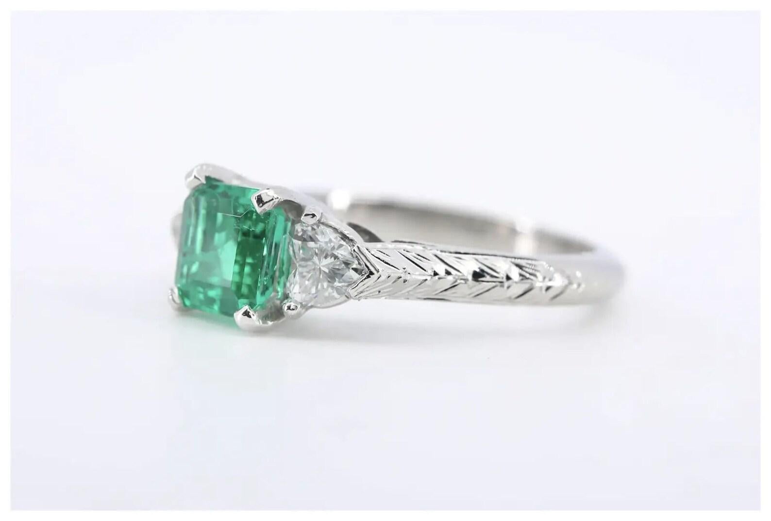 A handmade vintage Emerald and Diamond ring crafted in platinum.

Centered by a very fine emerald cut 1.02 carat Colombian emerald of intense green color.

Framed by a pair of 0.40ctw heart shaped brilliant cut diamonds of G color and VS2