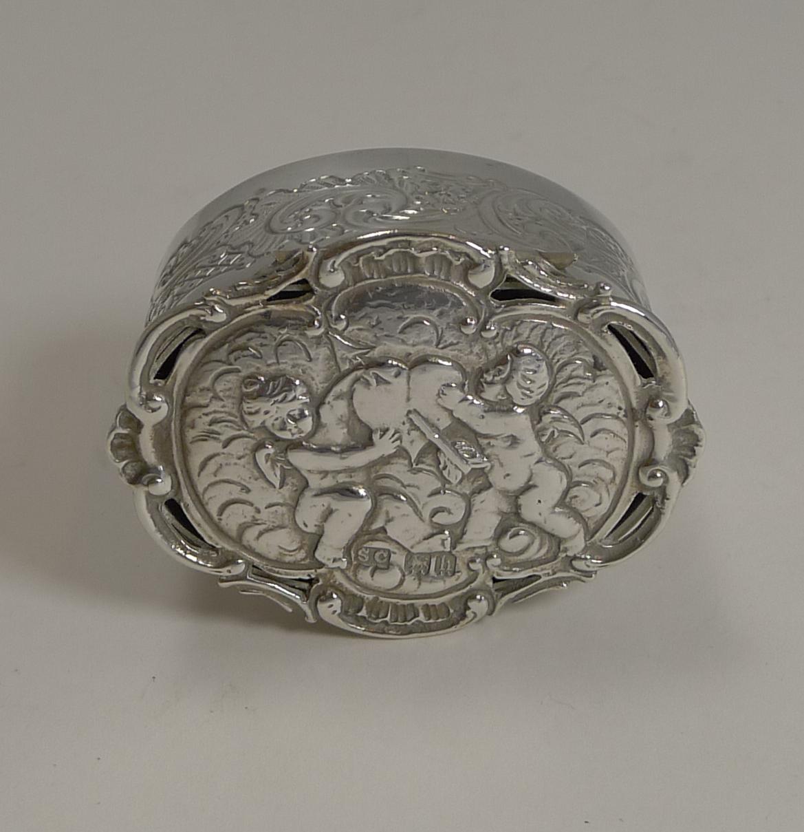 About as charming and romantic as they come, this Edwardian silver box has a beautifully decorated hinged lid with a cherub either side of a heart with an arrow through it. The shaped border of the lid has some pierced or reticulated