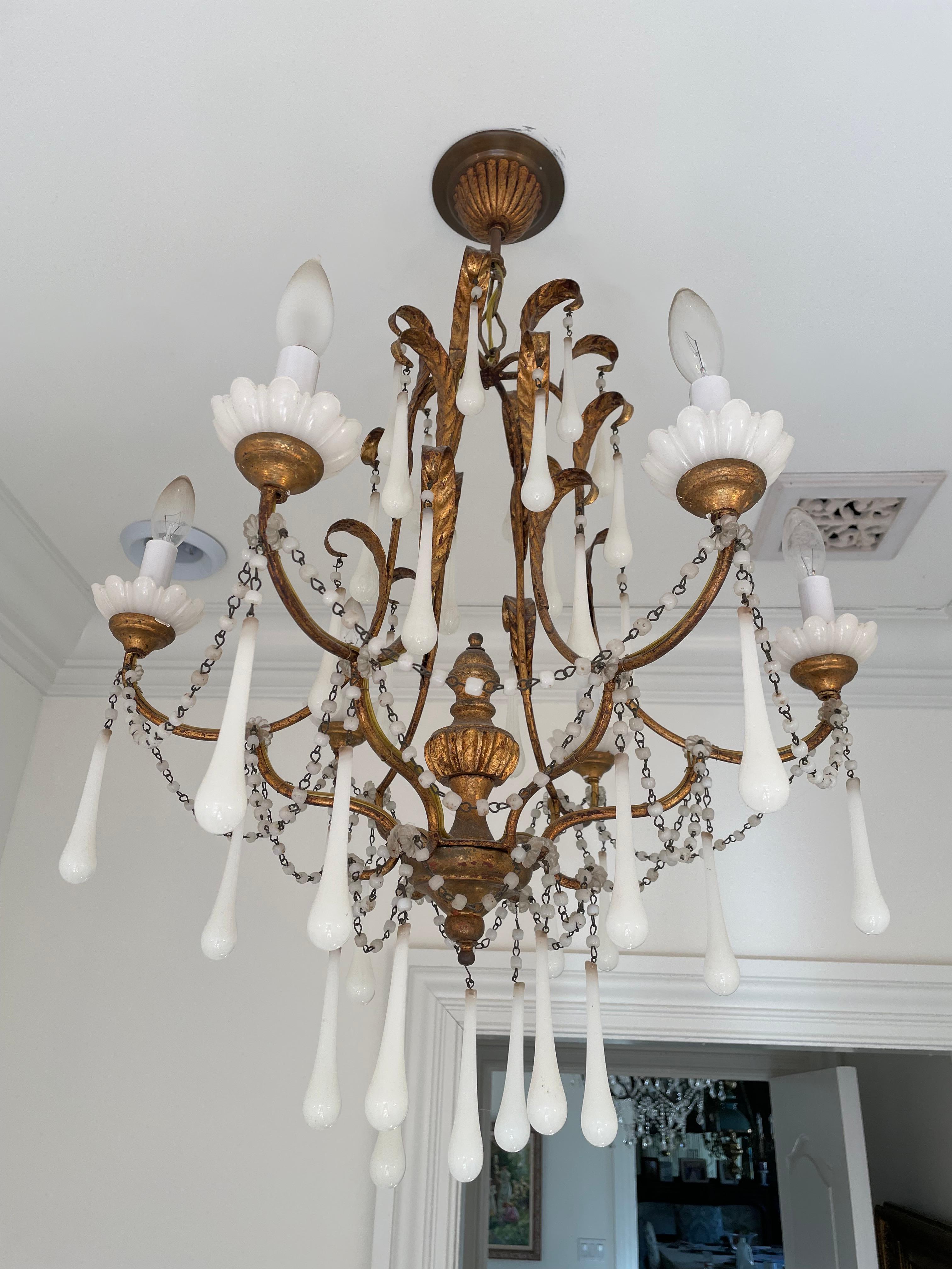 This chandelier is gilt metal with leaves and 6 arms having elegant opaline bobeches. It is dripping with strands of opaline beads and crystals. There is a sphere in the center and has the original fluted canopy. The white opaline beads and crystals