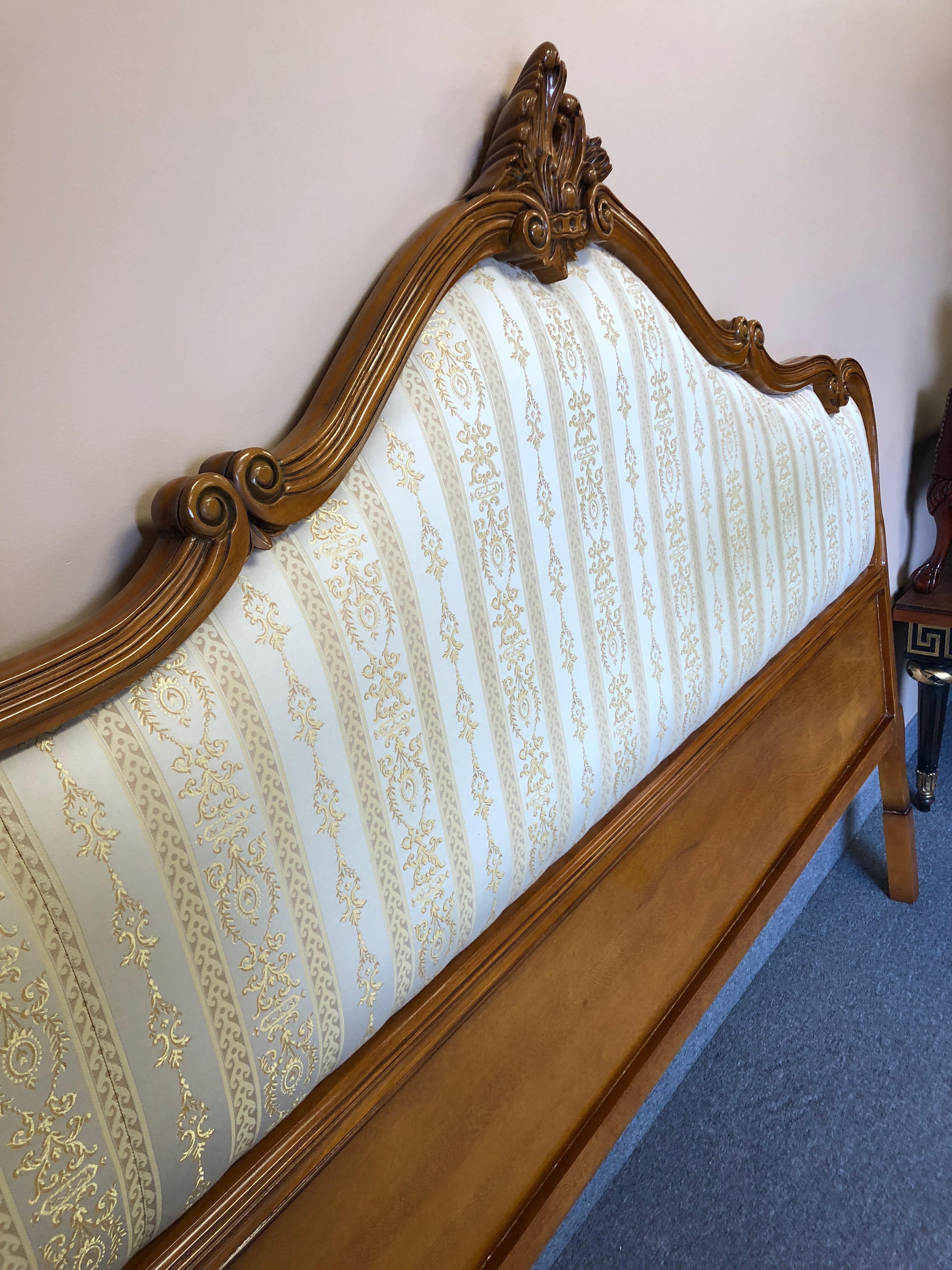 A stately large carved fruitwood king sized headboard with elegant gold and cream neoclassical print silk blend upholstery. By Girard Amelia.
 