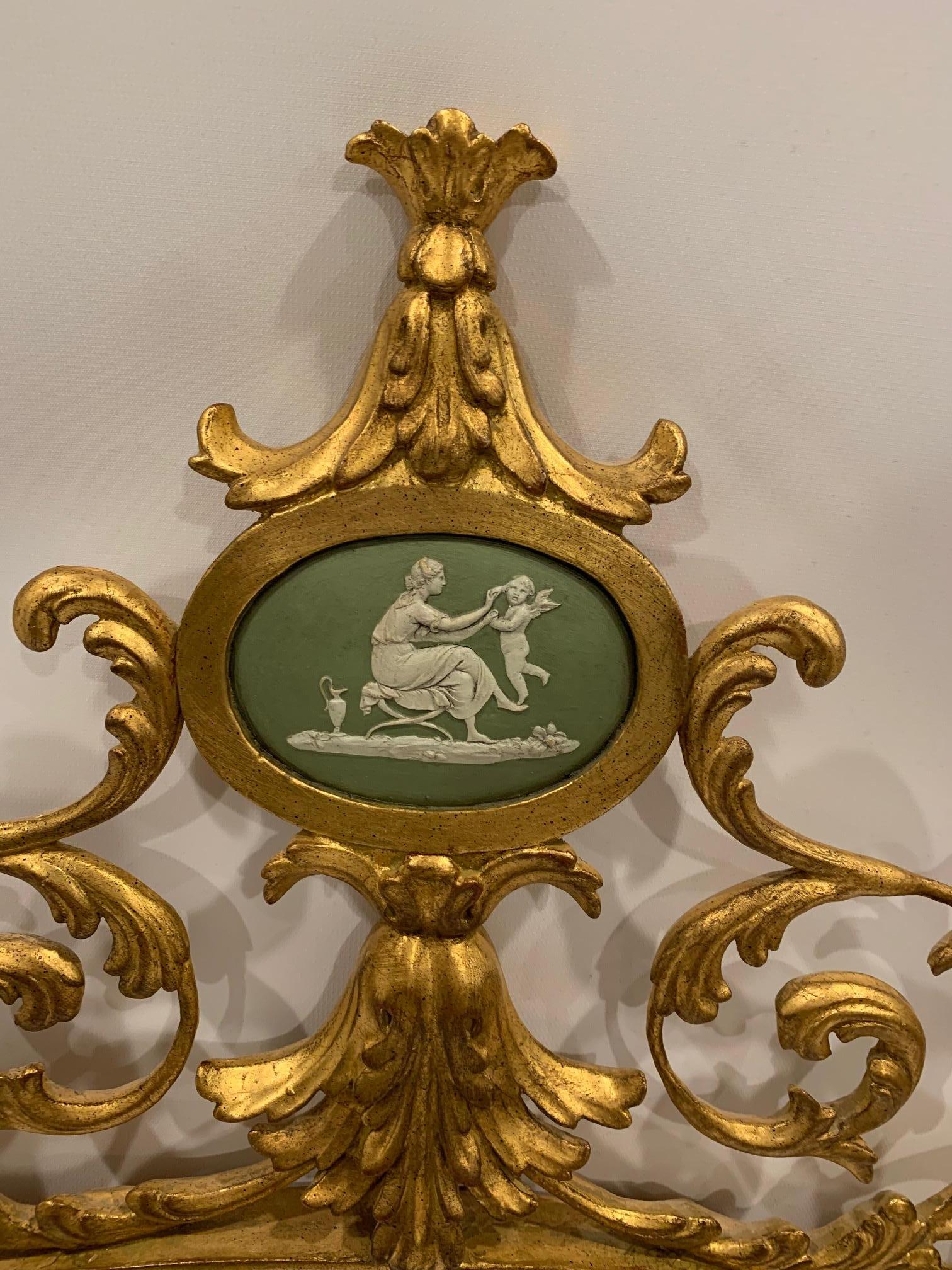 Romantischer ovaler Vergoldungsspiegel mit ausgefallenen Schnörkeln, abgeschrägtem Spiegel und wunderschönem grün- und cremefarbenem Wedgewood-Kameenmedaillon im oberen Bereich. Der Spiegel ist 26,5 x 16,75.