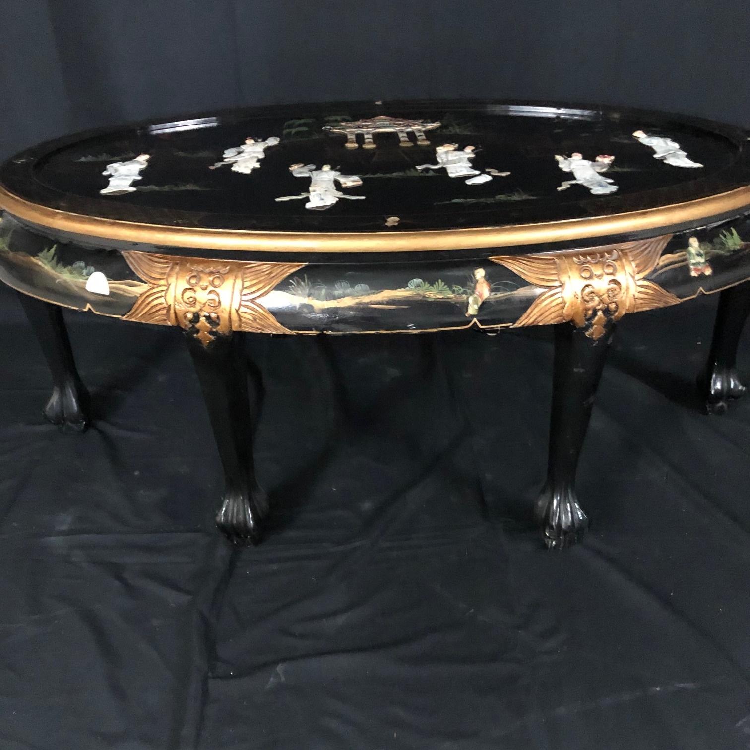A beautiful vintage Chinese coffee table in lacquered and painted wood from the mid-20th C. The wooden, oval frame is decorated with painted floral details and stunning mother of pearl figural inlays. The intricate delicately sculpted mother of