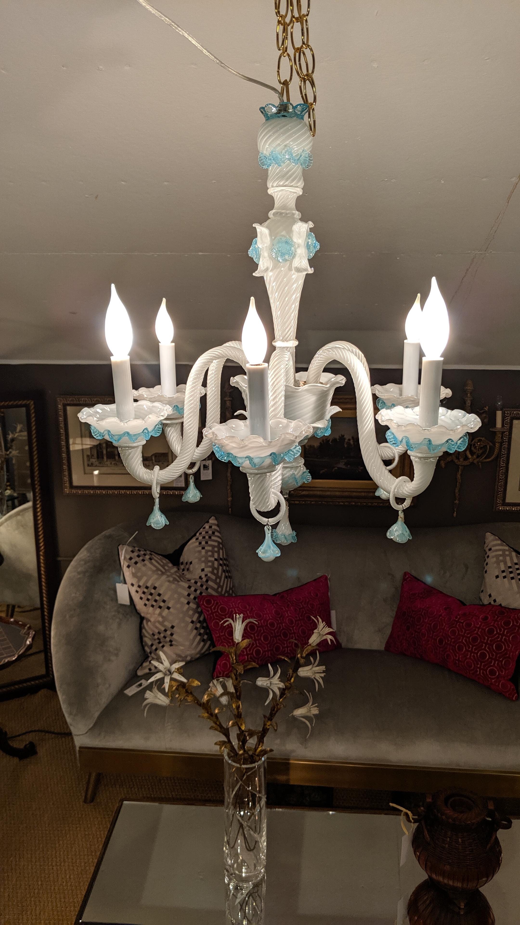 Murano chandelier with white cased glass and aqua adornments. The white glass has a twisted design with applied flowers and ruffles. Each arm has a ring with flower decoration; each bobeche has a scalloped rim. There is a matching Murano glass
