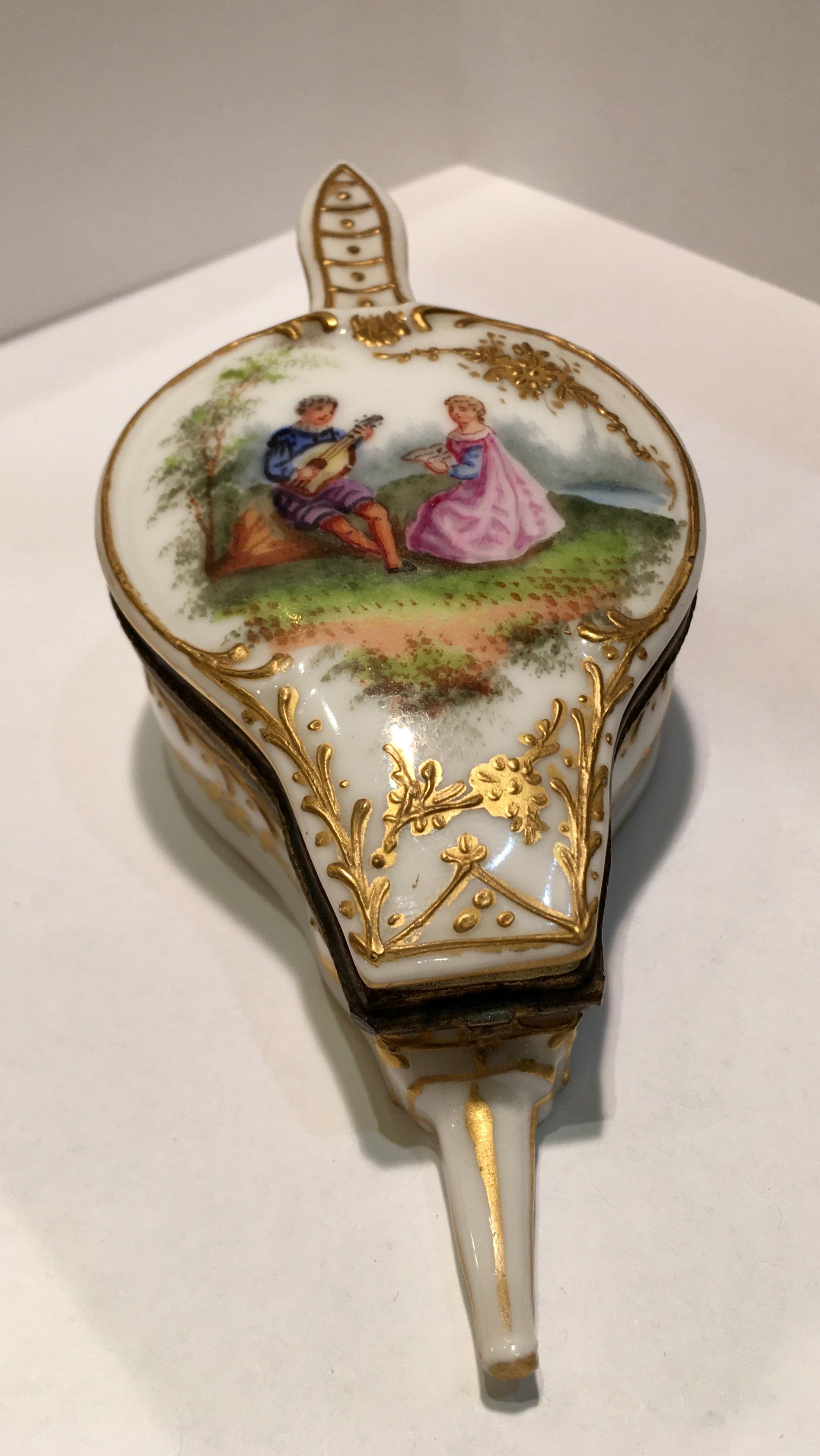 Exquisite antique French box, from the 1890s, is a handmade and hand painted miniature porcelain box with hinged lid and is shaped like a fire bellows. The interior of the box is hand painted in rich 24 karat gold. Lid features a romantic vignette