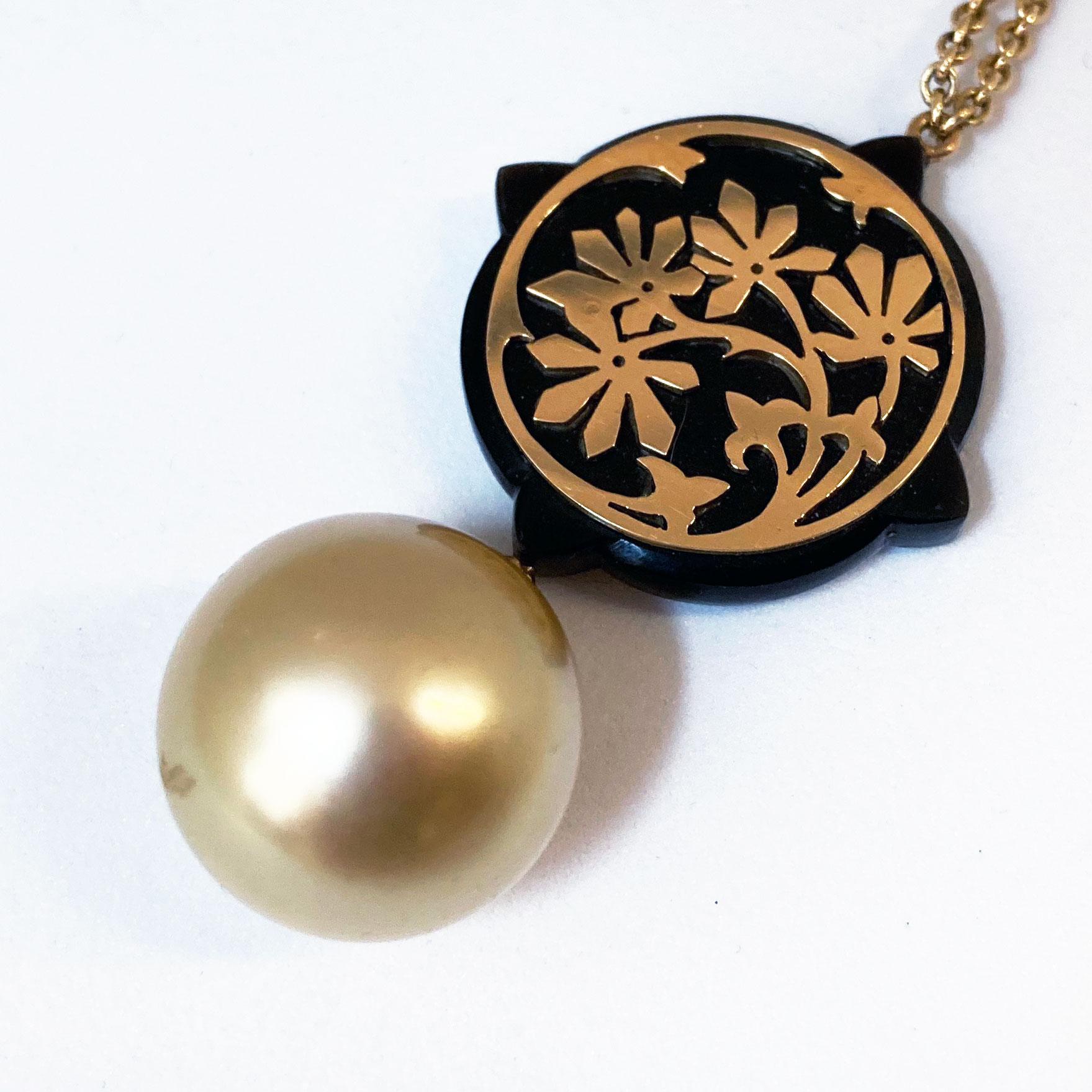 A delicate and romantic golden perfectly round South Sea Pearl (14.9mm) pendant crafted in 18 Kt rose Gold and black Horn. The Gold ornaments depict a floral style. The pendant comes with a timeless anchor 18 Kt rose Gold chain. Length: 52 cm.