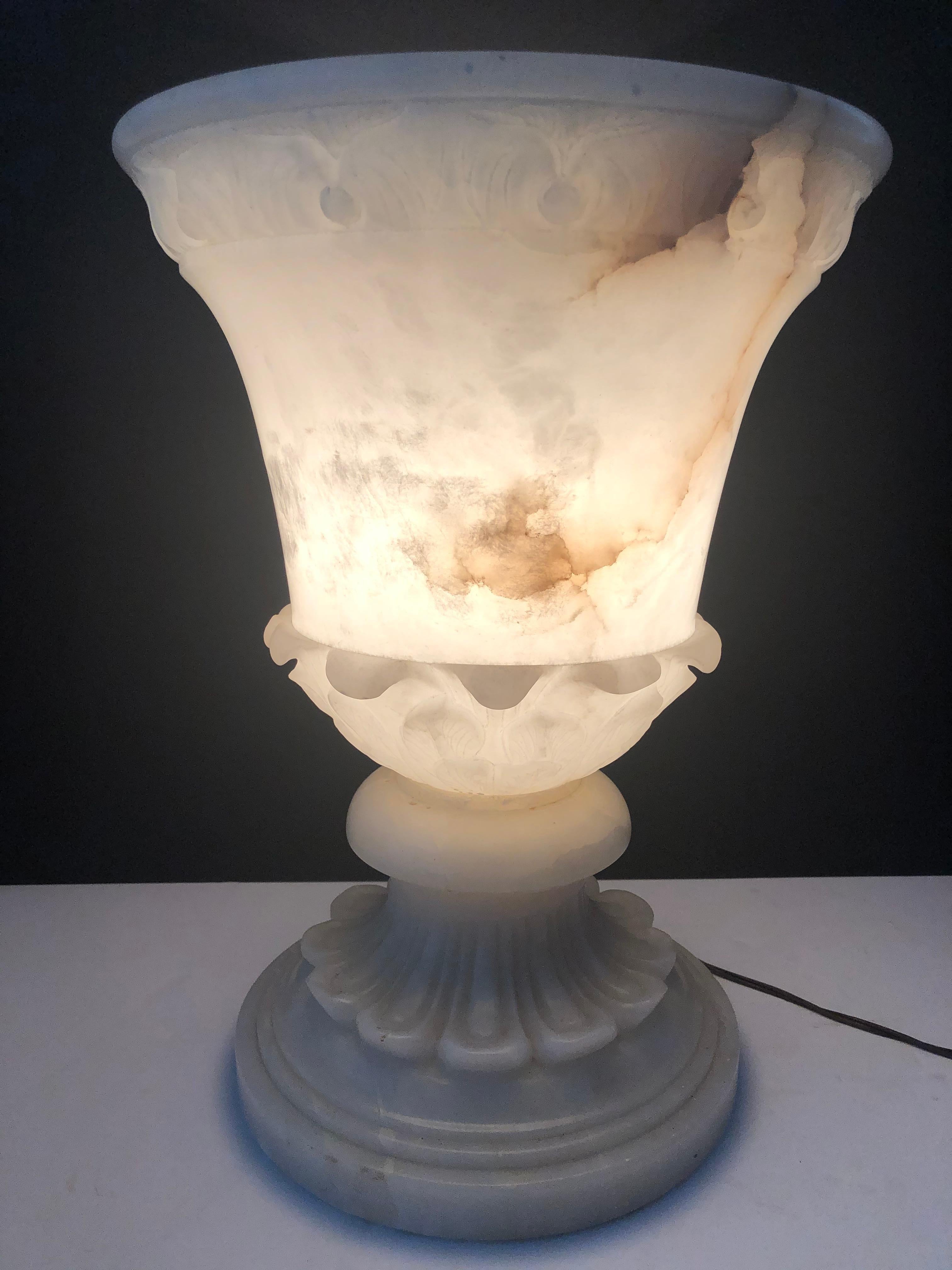 A stunning alabaster torchiere style table lamp. Made in Italy, this torchiere is of a larger size than most. It has carved detail throughout. When lit, its veining in the alabaster shows and it provides a soft ambient light. The dimmer switch
