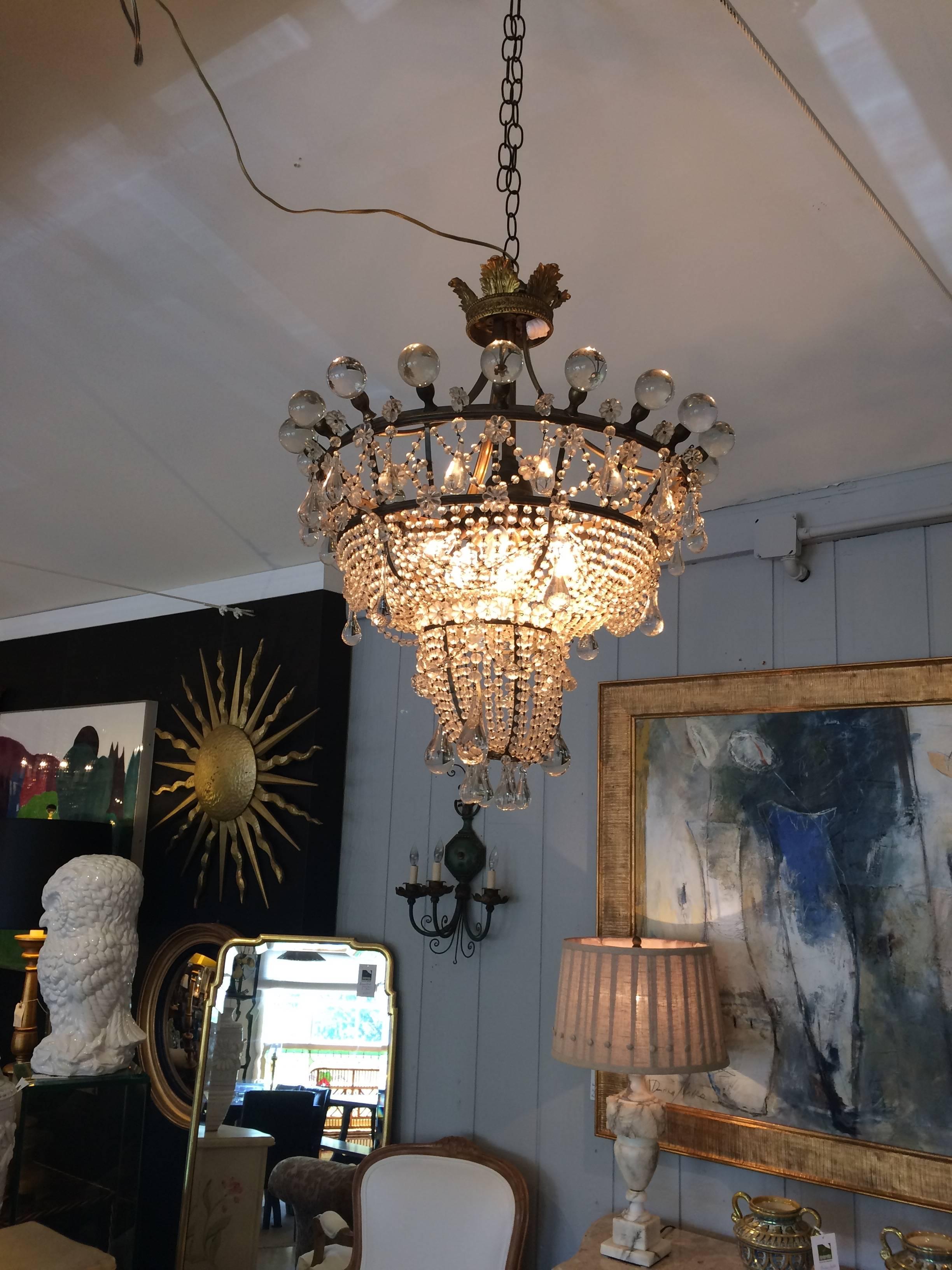 Unbelievably romantic and rare chandelier having amazing large crystal balls around the circular top with graduated circular tiers bejeweled with small balls and large tear shaped crystals. A regal brass crown tops it off and there are seven