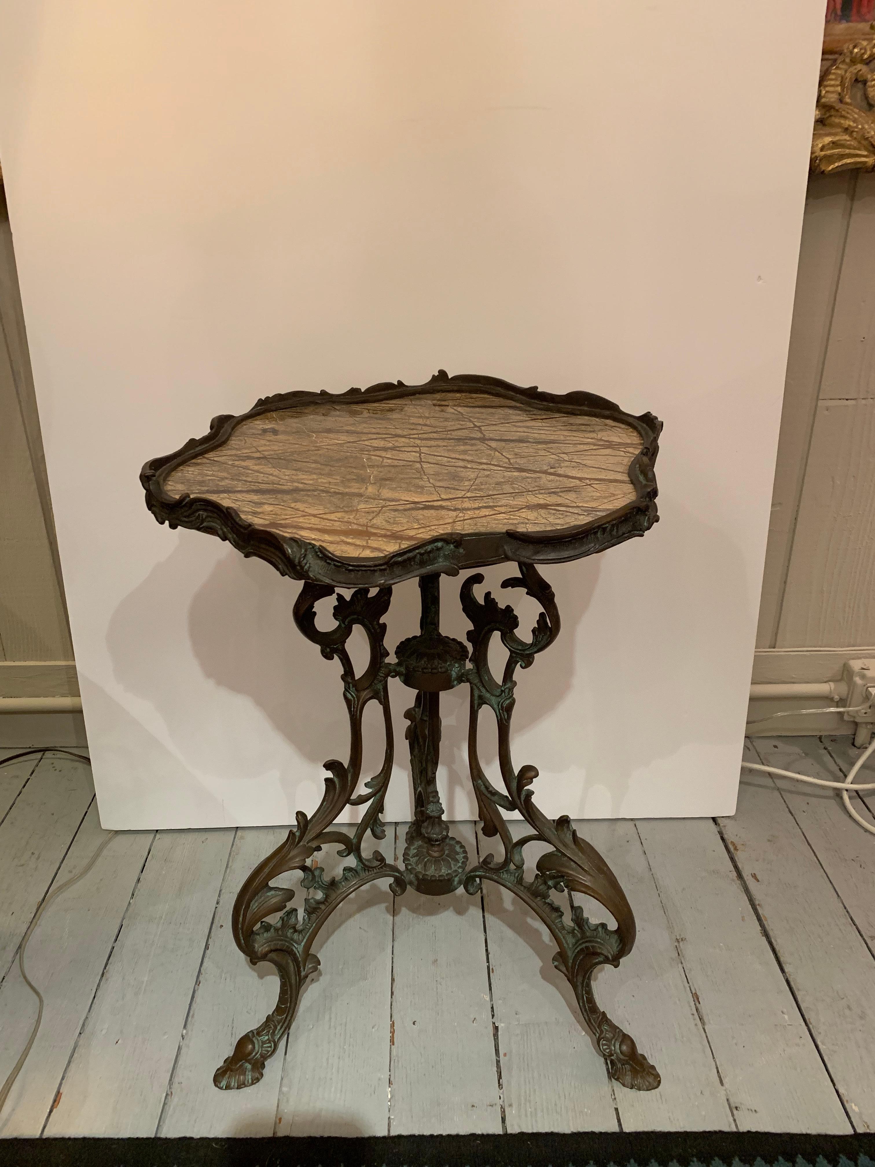 A gorgeous vintage side table having an ornate bronze curliecue base with 4 hoof feet and ancanthus leaf motife, topped with scalloped shape marble and bronze gallery surround.
  