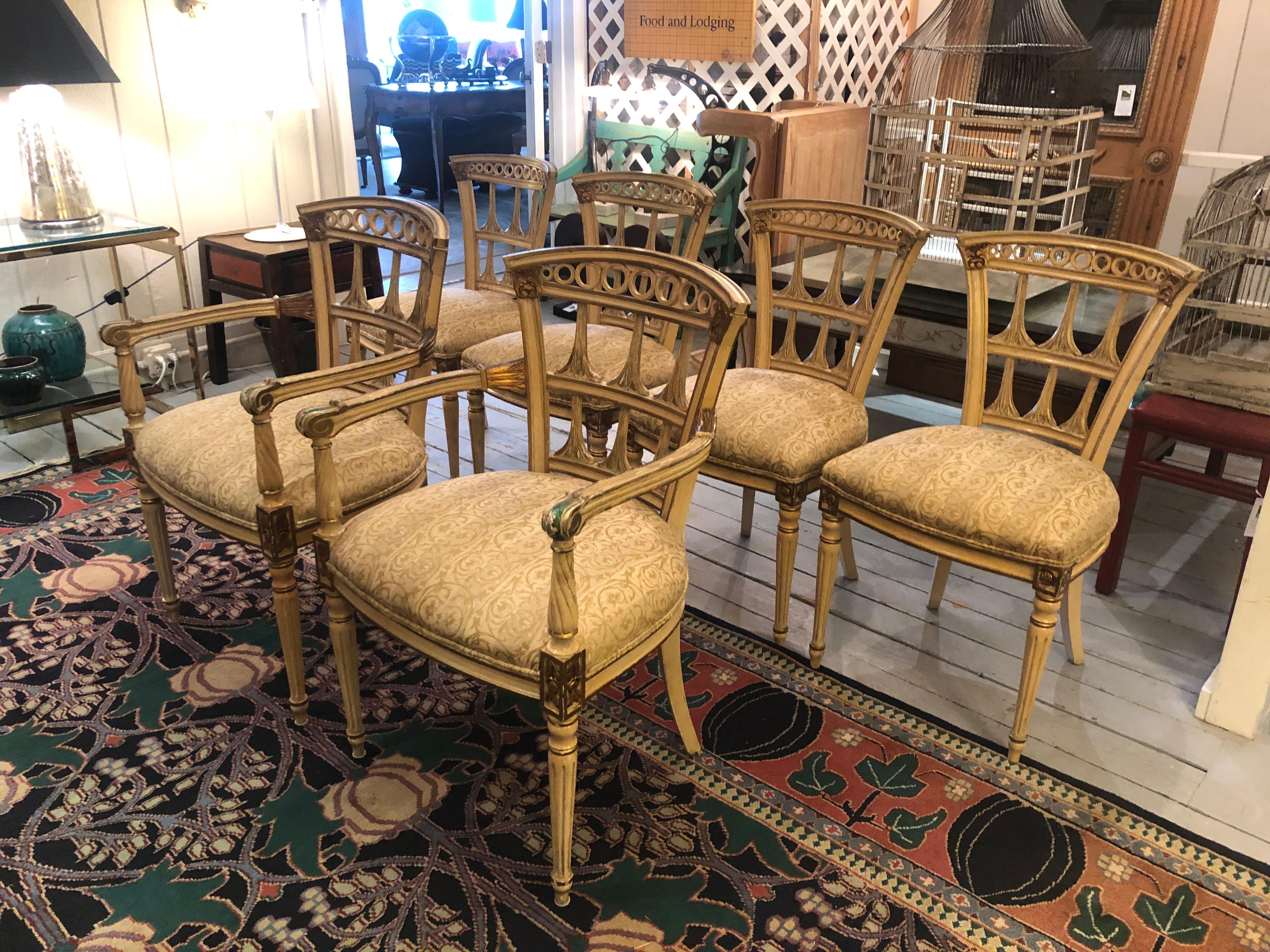 A romantic vintage set of 6 Italianate style carved wood painted and gilded dining chairs including two armchairs and 4 sides, having beautiful aged patina and neutral color of yellowish cream and gilt with some undercoat of green showing through