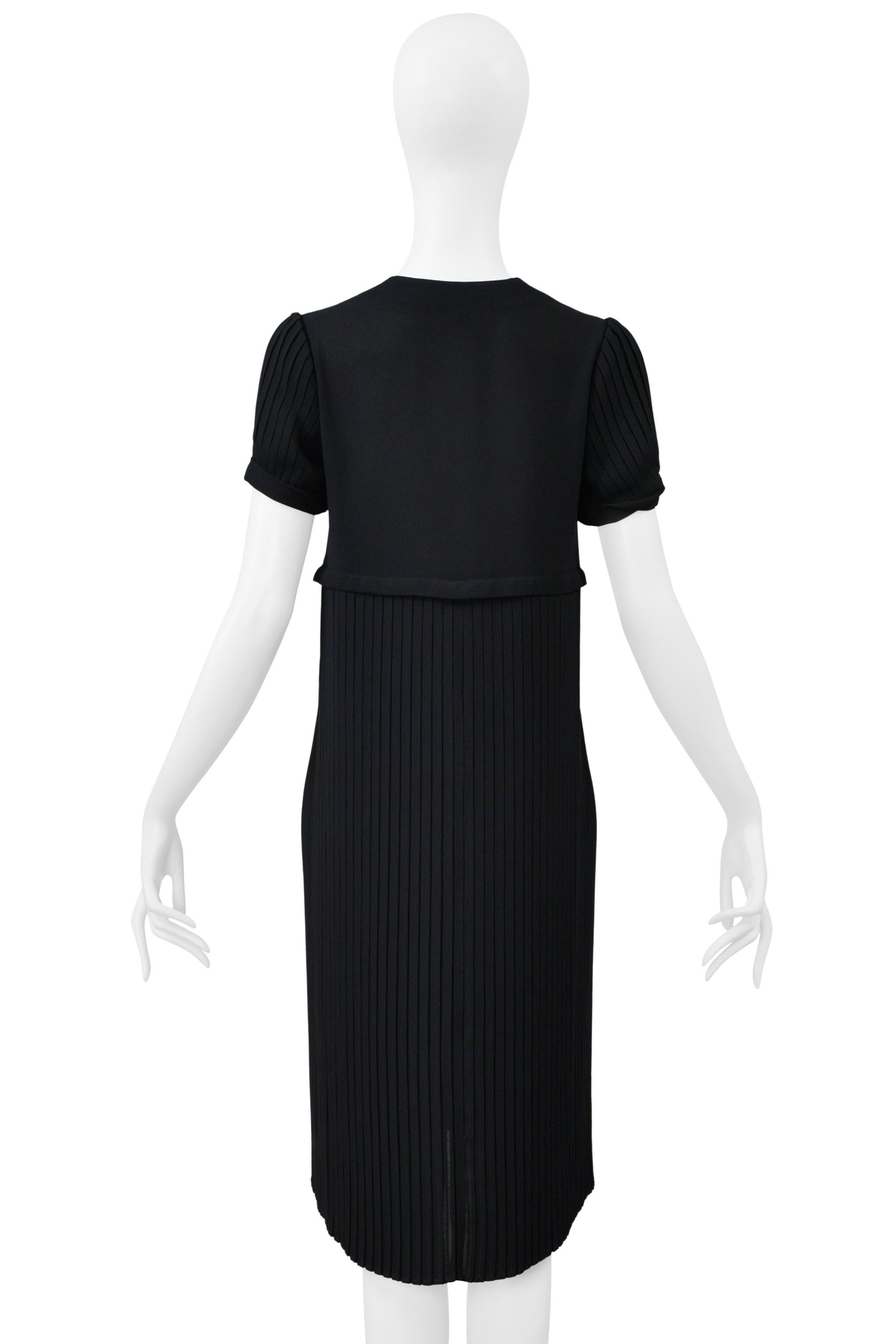Resurrection Vintage a le plaisir de vous présenter une robe noire vintage à manches courtes Romeo Gigli de la collection printemps 1997, avec un corps et des épaules plissés, un nœud sur le buste, une encolure carrée, et une longueur au-dessus du