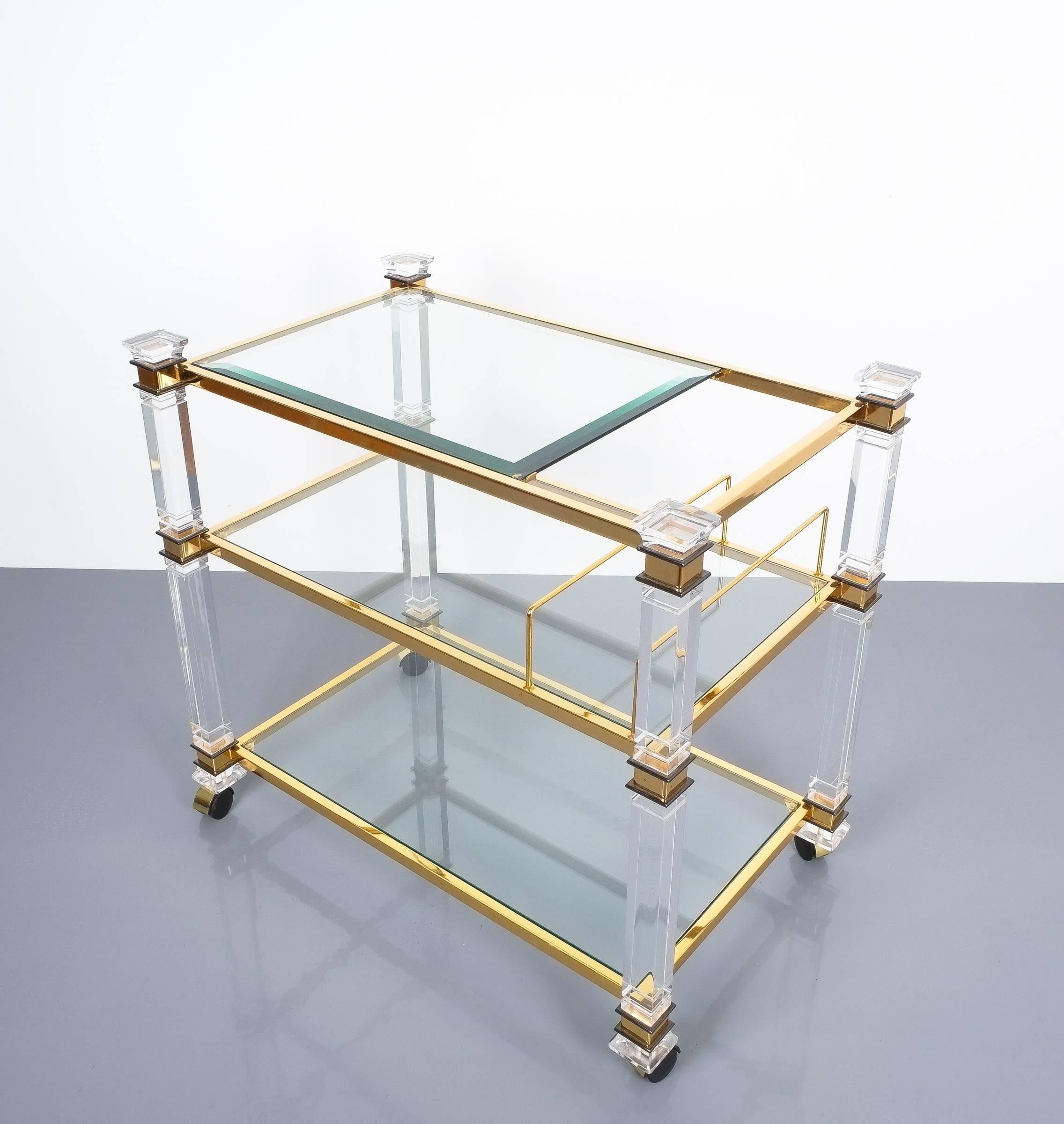 Romeo Rega bar cart table Lucite glass gold brass, 1970. Classical bar cart or small side board by Romeo Rega consisting of Lucite pillars and gilt brass joints. Three clear glass trays, the top tray has got a bevelled trim. The cart is in excellent