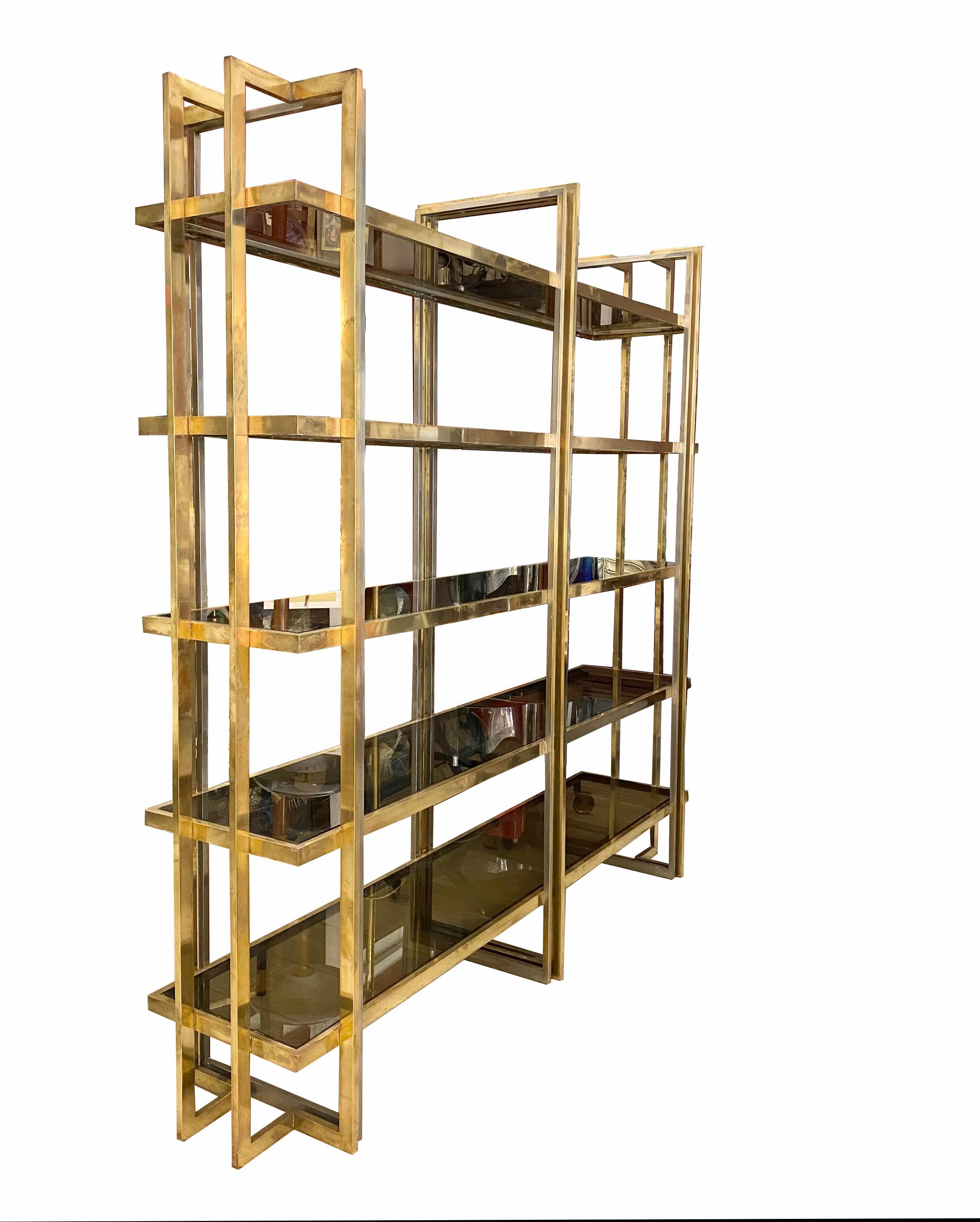 This brass etegere was designed and manufactured in Italy by Romeo Rega in 1976. It is embellished with an important detail: the structure is made of original smoked glass shelves in perfect condition. The shape of the shelving is designed to offer