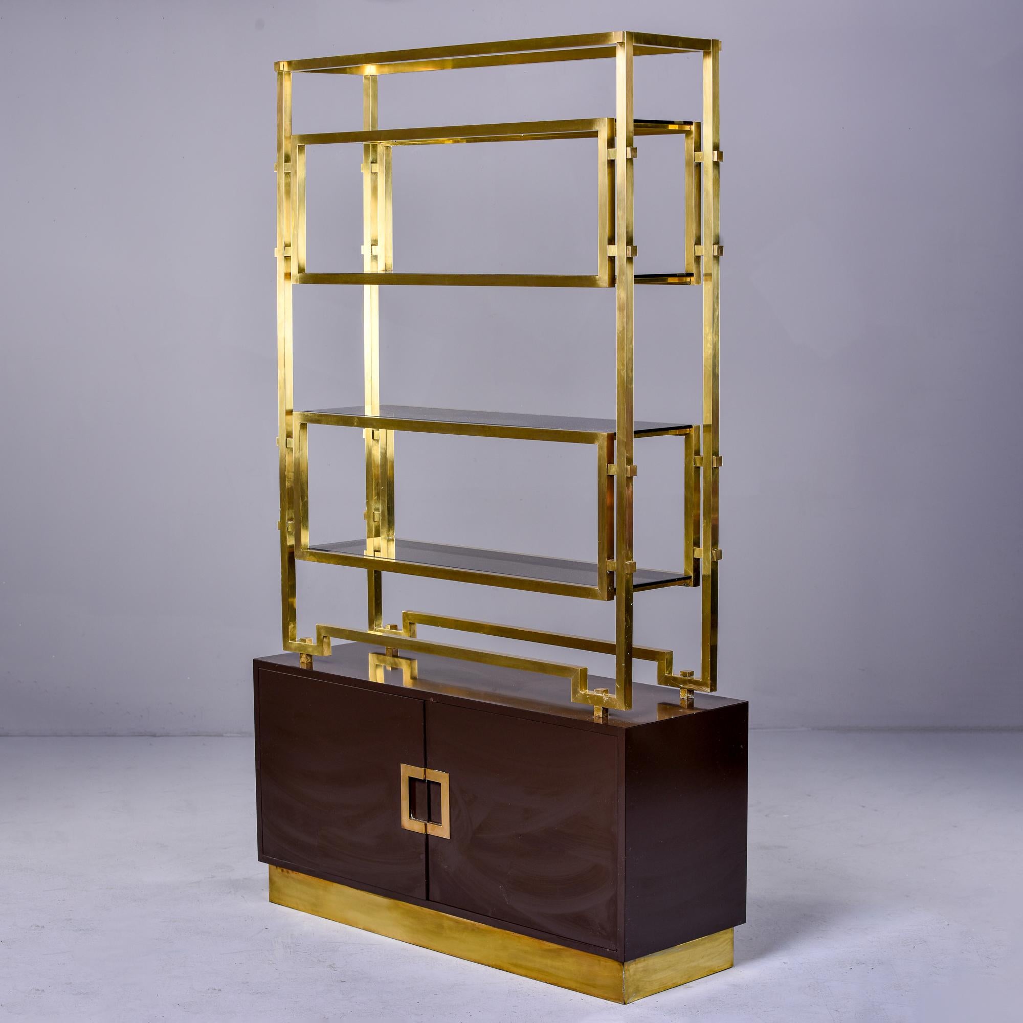 Found in Italy, this circa 1970s shelf cabinet is attributed to Romeo Rega. The base is an espresso colored enamel over wood with a brass base and hardware. Open internal storage compartment in lower cabinet. Top section has brass shelf frame with