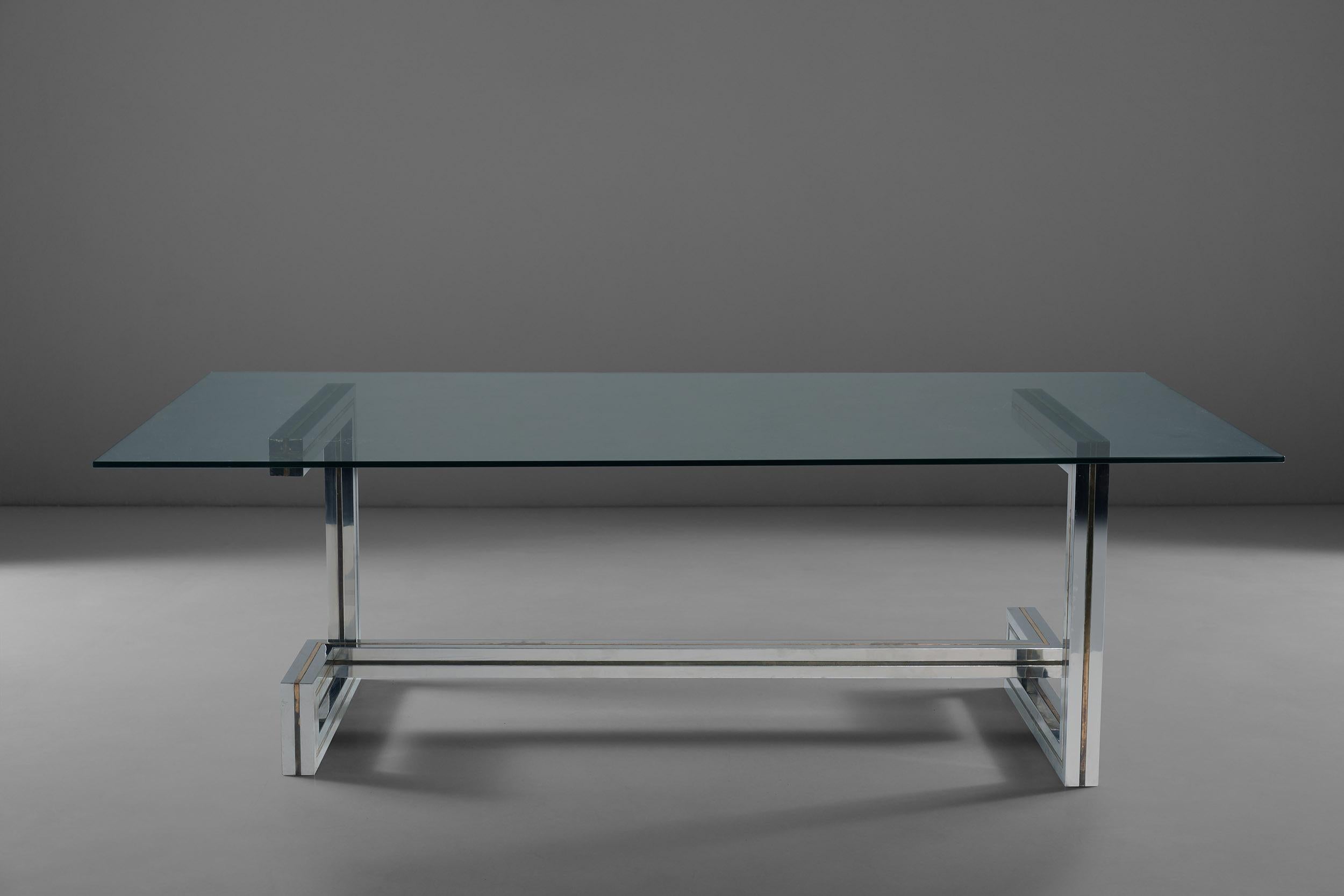 An amazing dining table designed by Romeo Rega made out of steel, brass and glass top. This table's structure plays with geometric lines, creating a clean yet original frame made out of steel and with brass inserts. This combination of material is