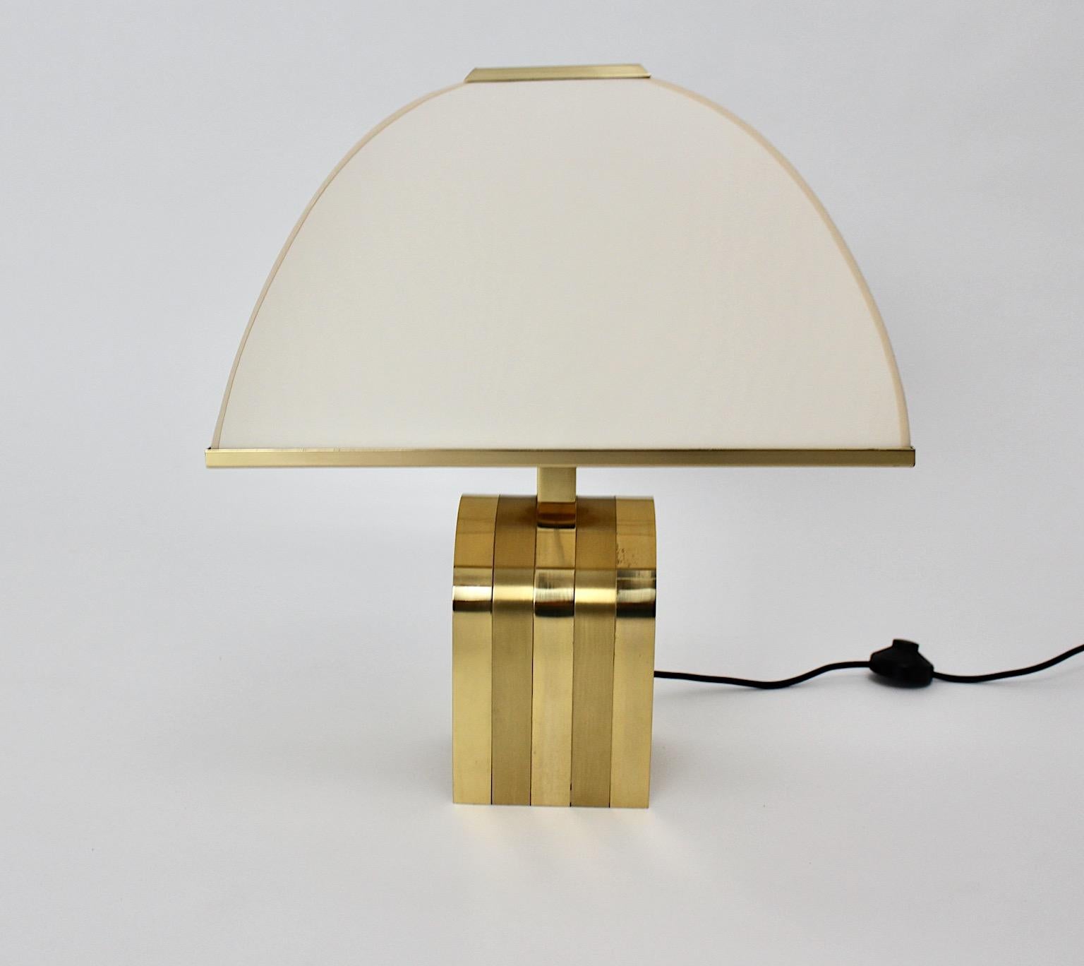 Hollywood Regency style vintage table lamp from brass and textile fabric shade by Romeo Rega Italy 1970s.
While the U like base from brass shows beautiful patina, the handmade lamp shade from textile fabric with brass trim in butter cream color