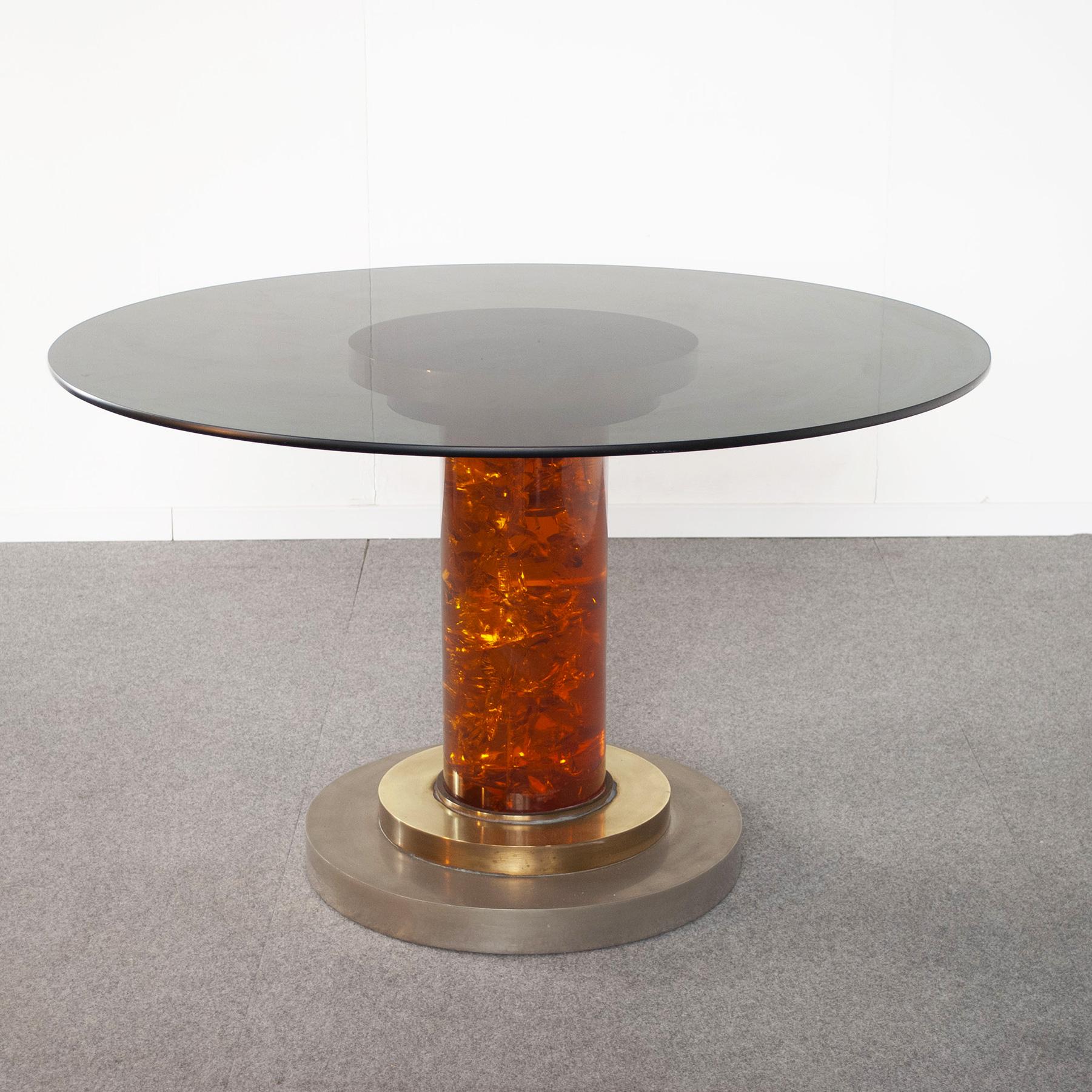 70er-Jahre-Tisch aus einer eleganten Mischung von Metallen mit poliertem Messing und Stahl-Finish. Der zentrale Sockel ist aus honigfarbenem Plexiglas mit einem Durchmesser von 20 cm gefertigt. Die Rauchglasplatte in der Abbildung ist 15 mm dick und