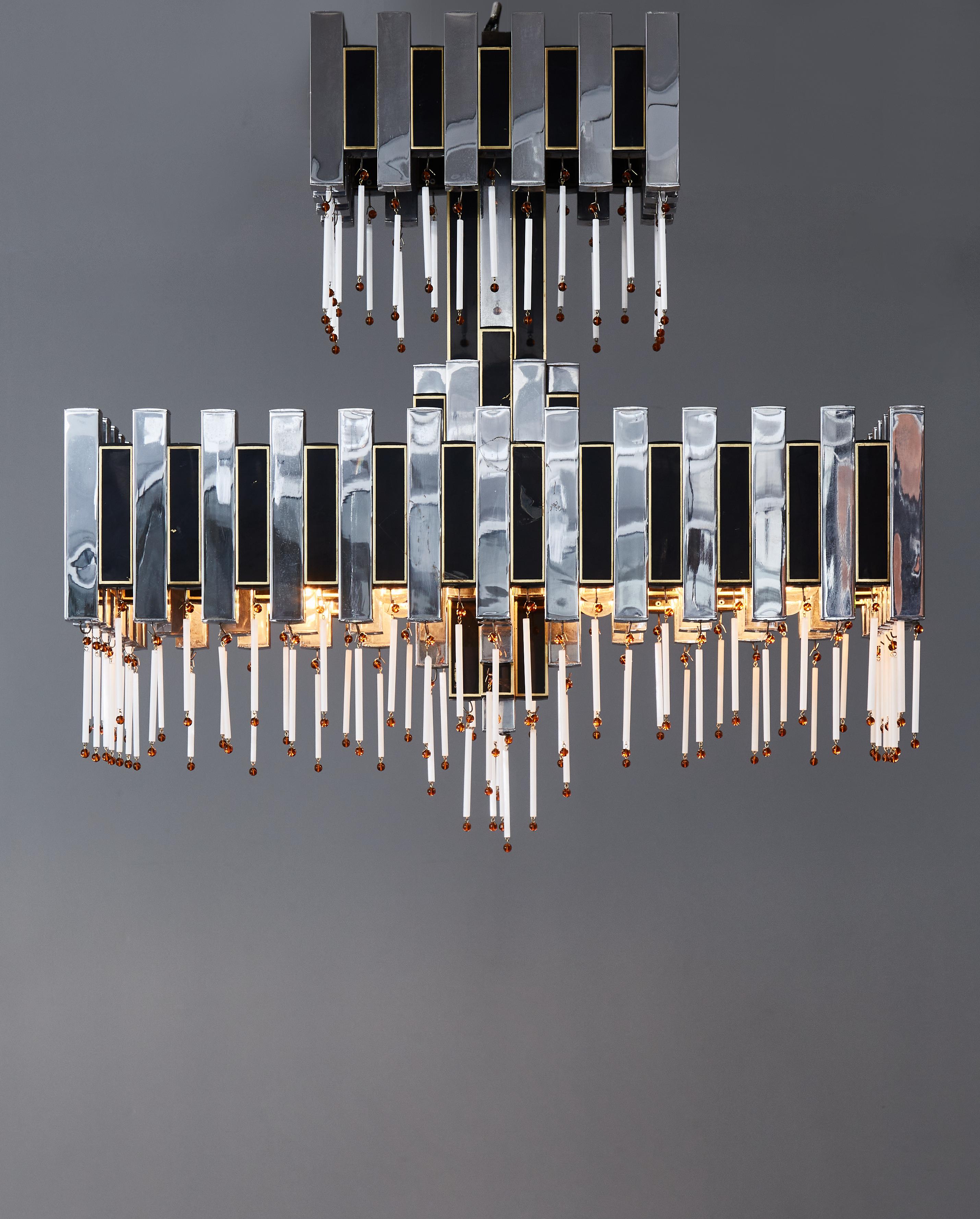 Chandelier by Romeo Rega made of small rectangular chromed metal piece, with one-in-two covered with a black and gold decor. White and orange pampilles are hung to each piece as well.