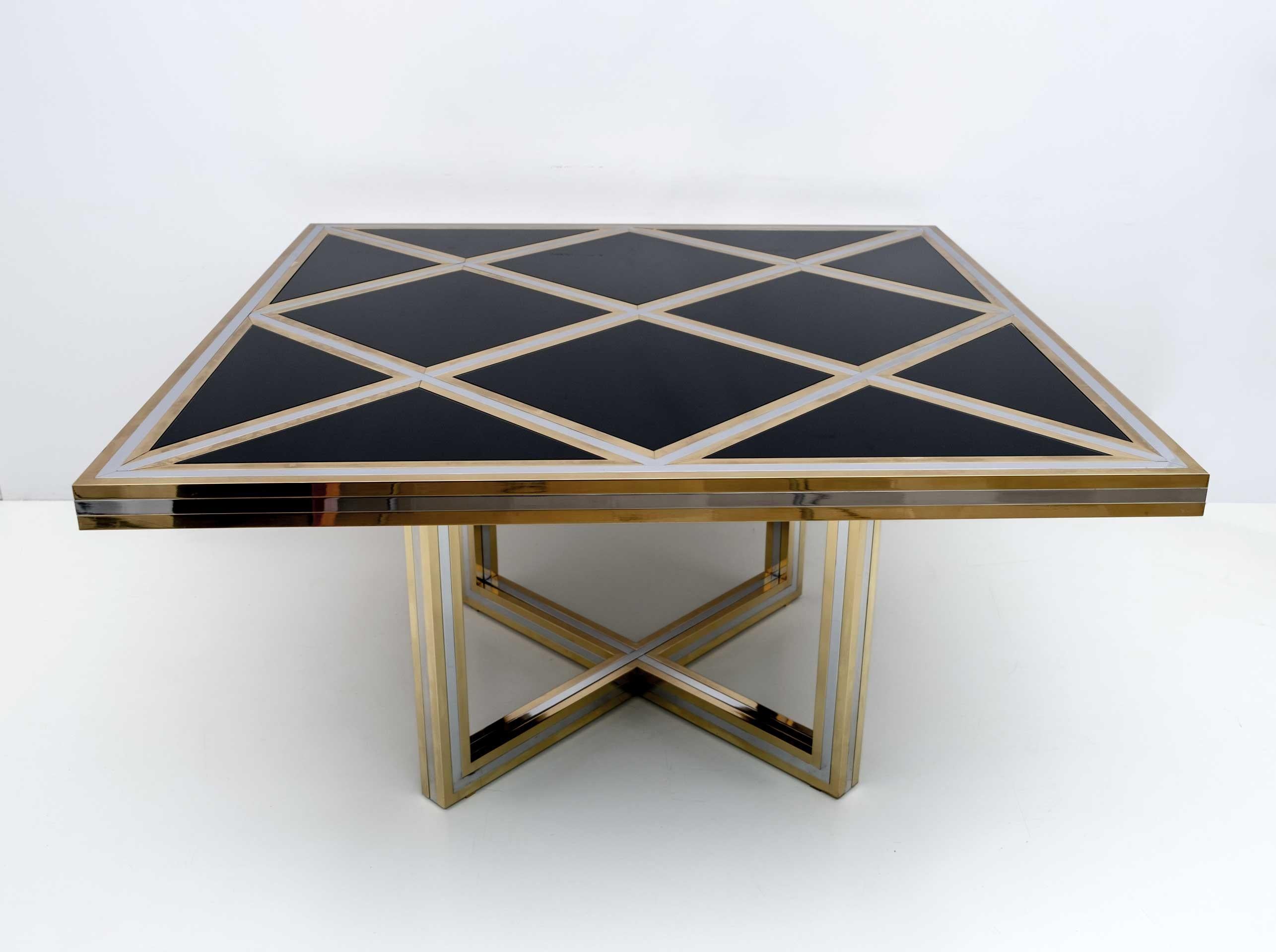 An intriguing designer piece, this large dining table deserves to be the focal point of your dining room. Symmetrical brass and chrome elements strike through a black glass top, the result is a stunningly elegant centerpiece for the dining room.