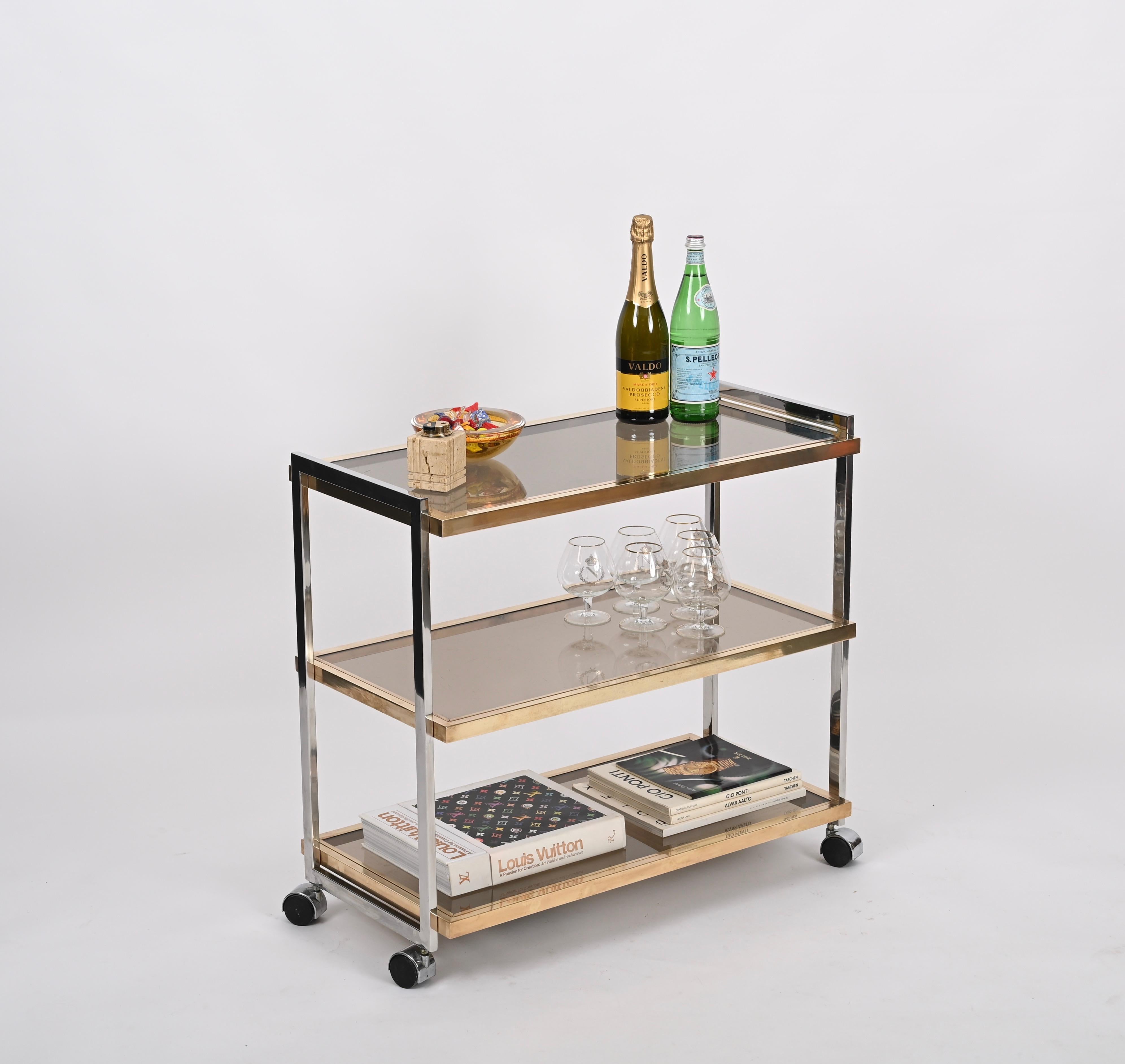 Gorgeous trolley bar cart fully made in solid brass and chromed metal. This wonderful and rare three level bar cart was designed by Romeo Rega and produced in Italy during the 1970s.

Each shelf of this sturdy serving table can be removed. The