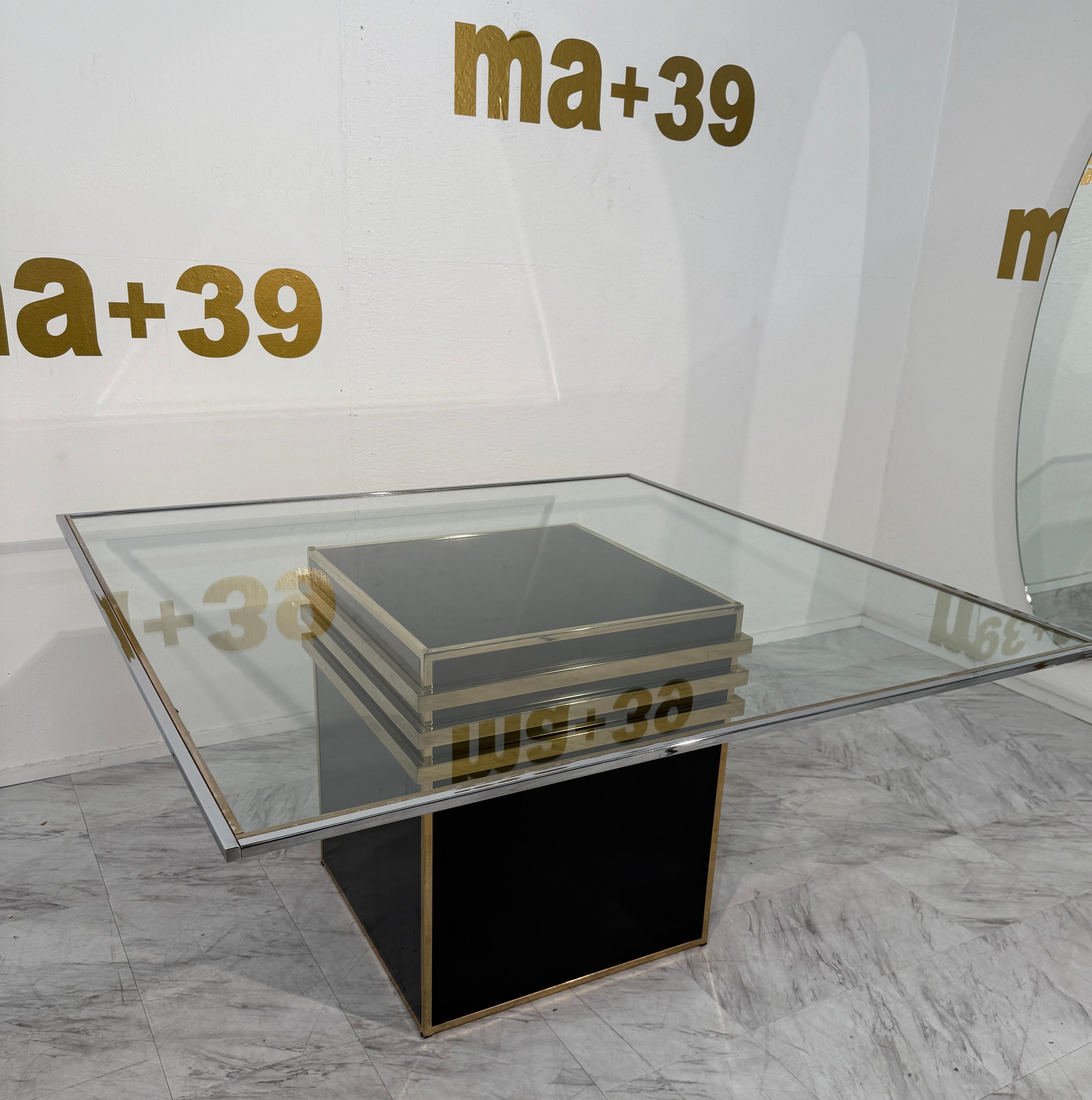 Striking Italian dining table by Romeo Rega, circa 1970s.
The table features a square beveled glass top supported by a sculptural pedestal base. The base is crafted in lacquered black with polished brass trim and three horizontal brass bands that